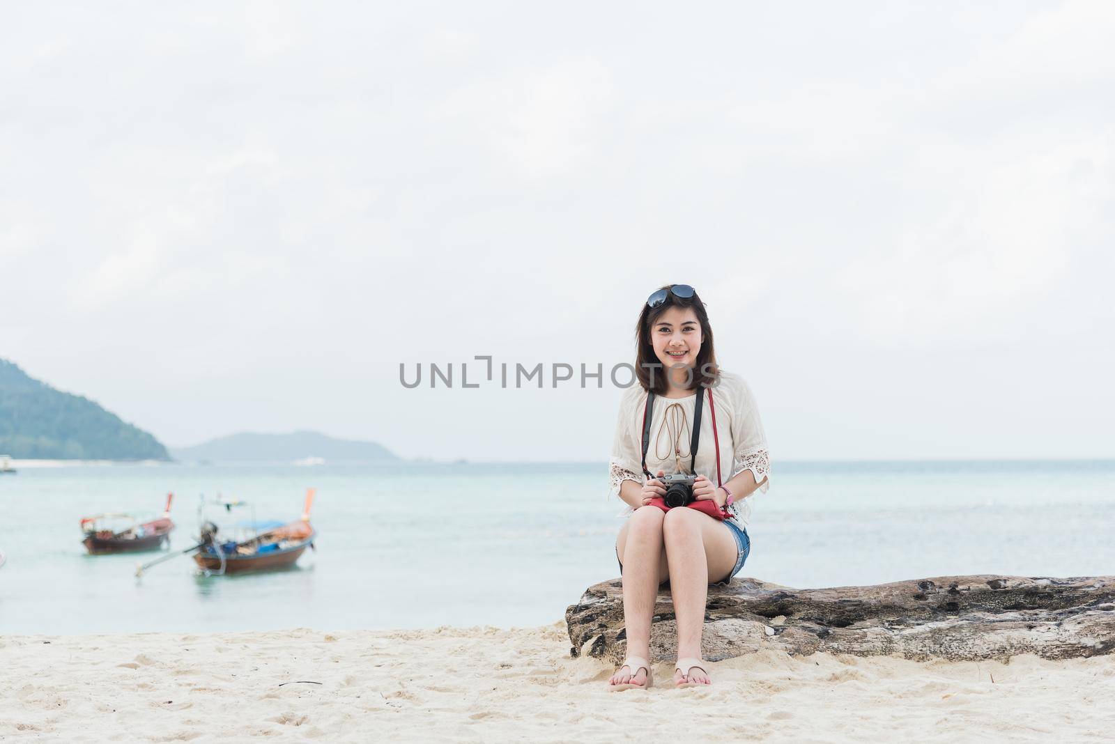 asia girl sitting and take photo on the beach