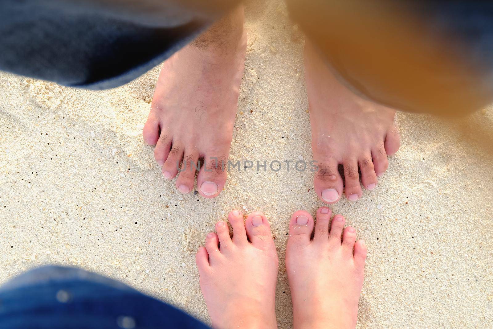 lover's feet on sand beach by Wmpix