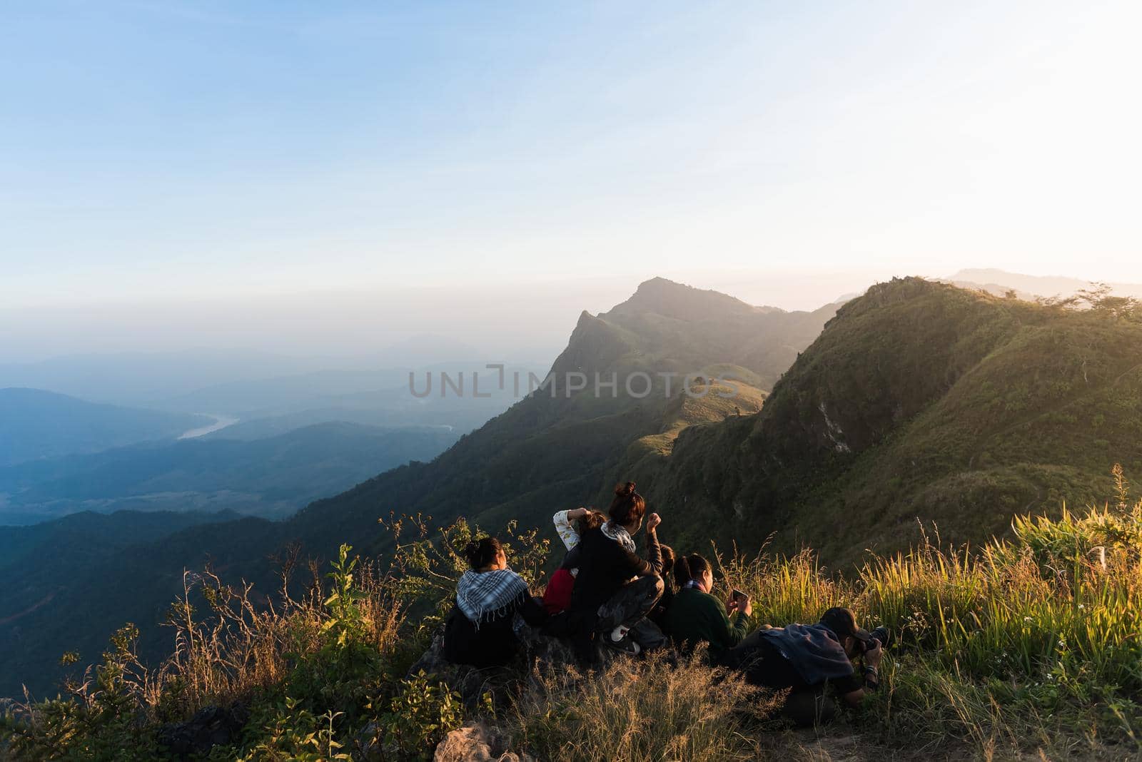 tourists with taking photo of a valley from top of a mountain