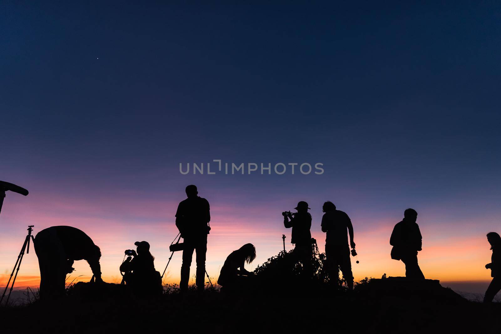 Photographers Silhouettes On Cliff Against Colorful Twilight Sky by Wmpix