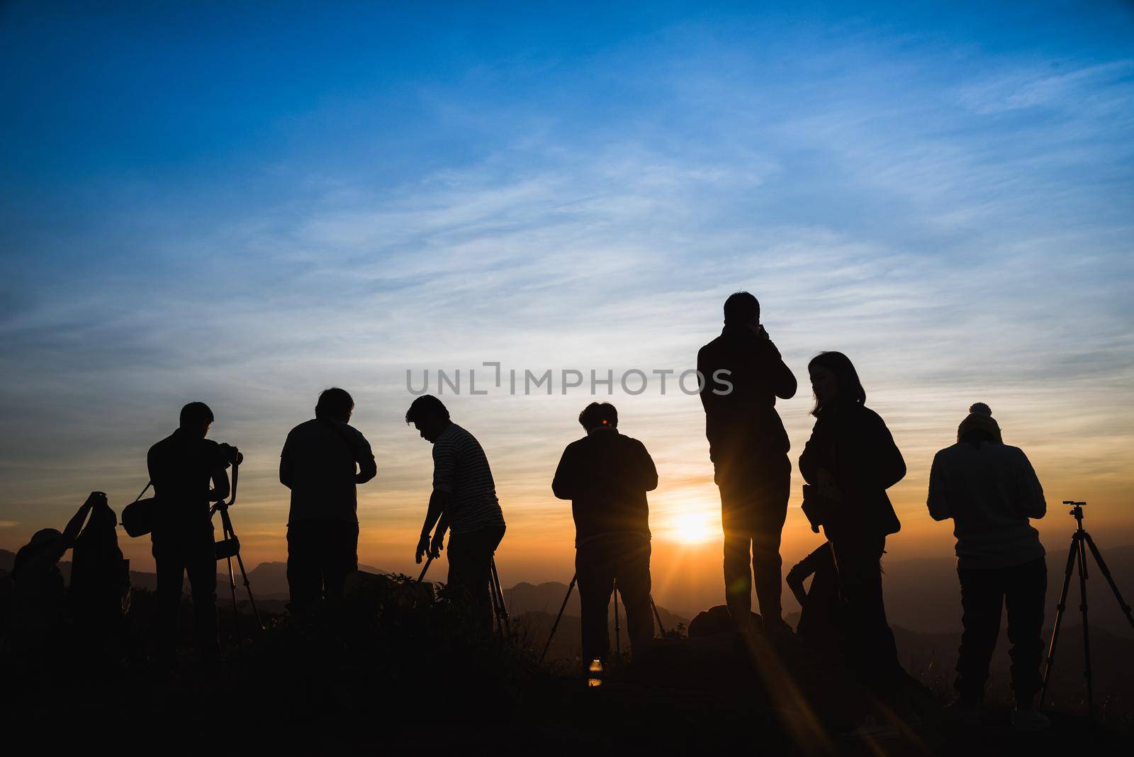 Photographers Silhouettes On Cliff Against Colorful Twilight Sky by Wmpix