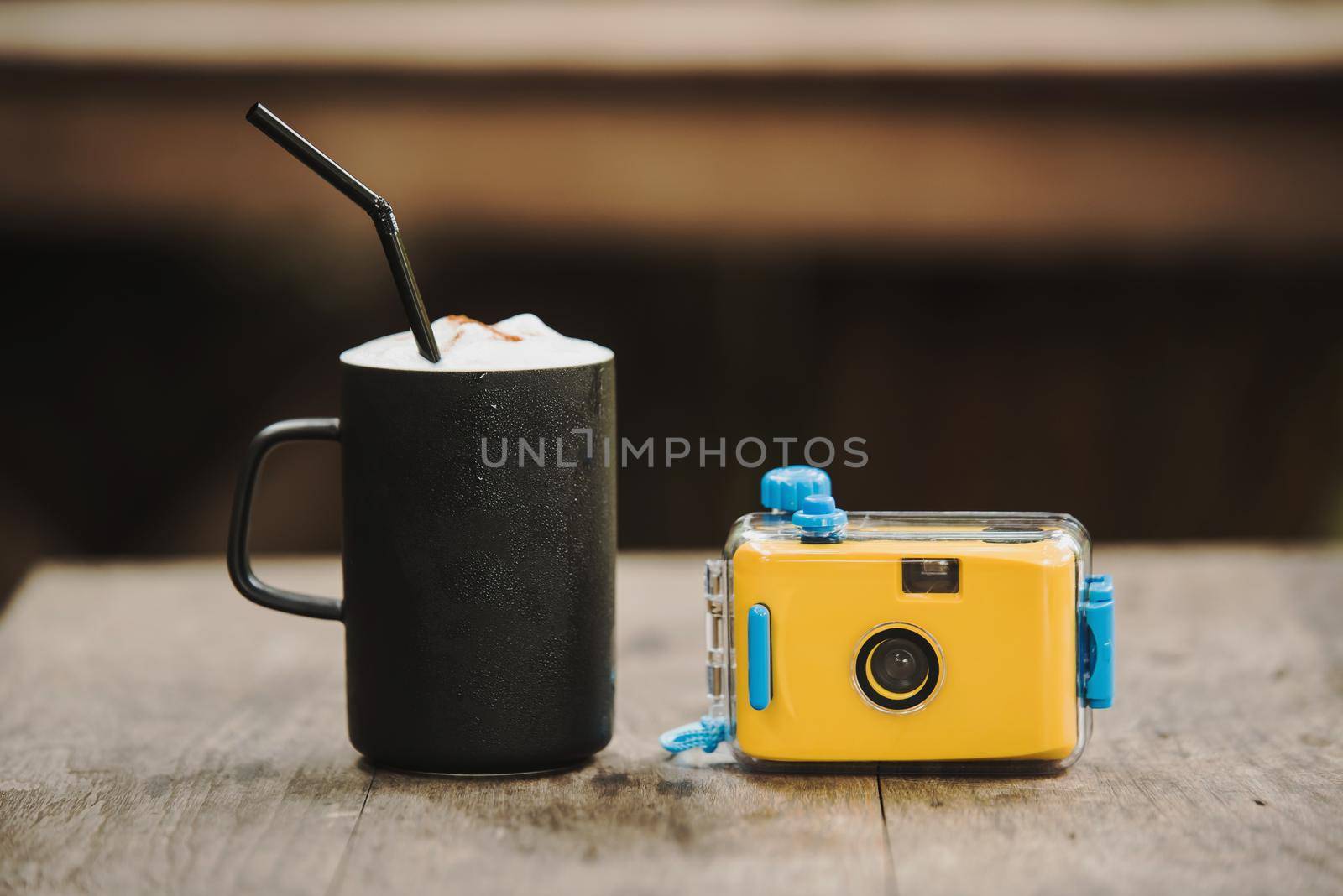 camera with coffee in cafe on wood table
