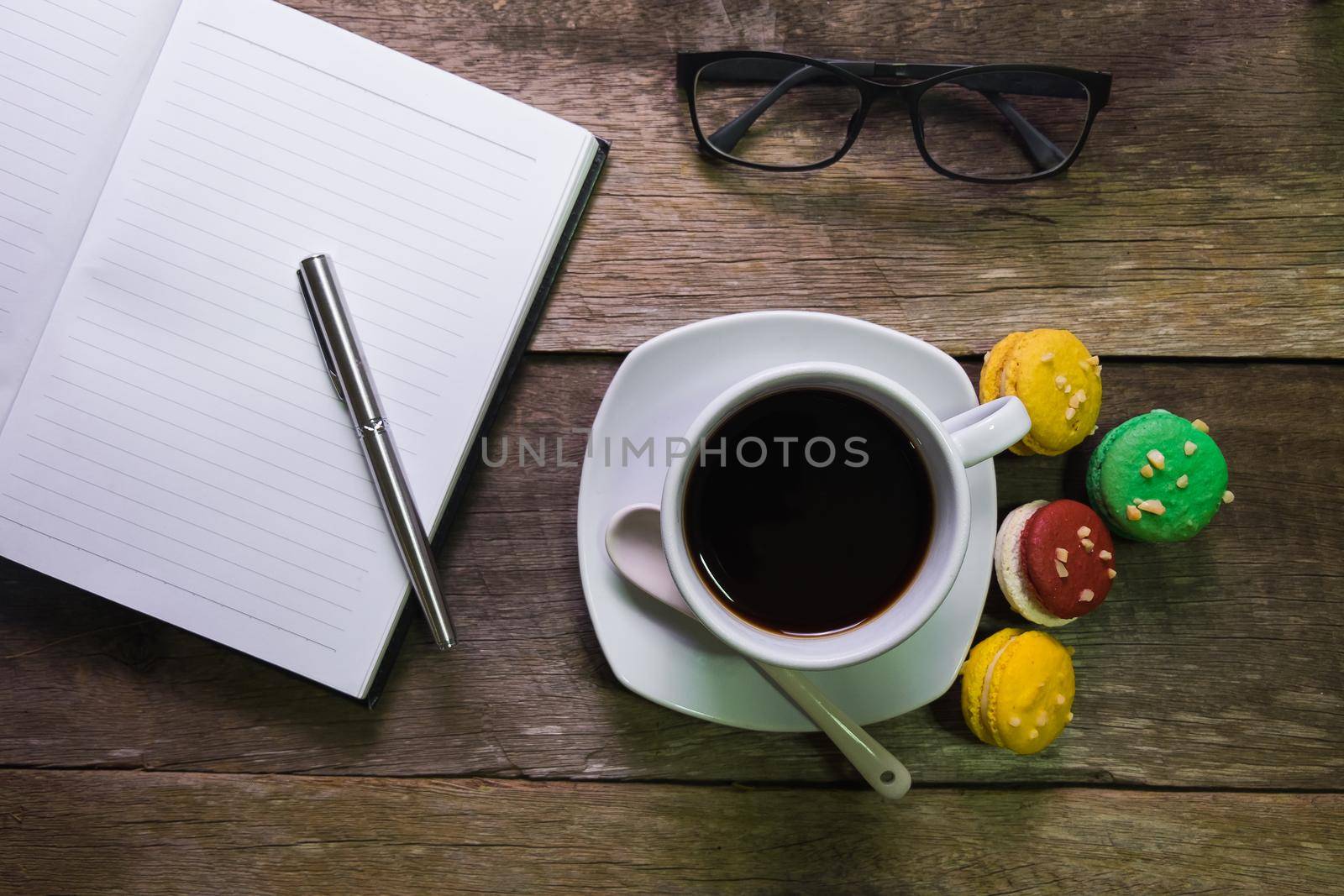 notebook on rustic wood with macaroon cup of coffee and glasses by Wmpix