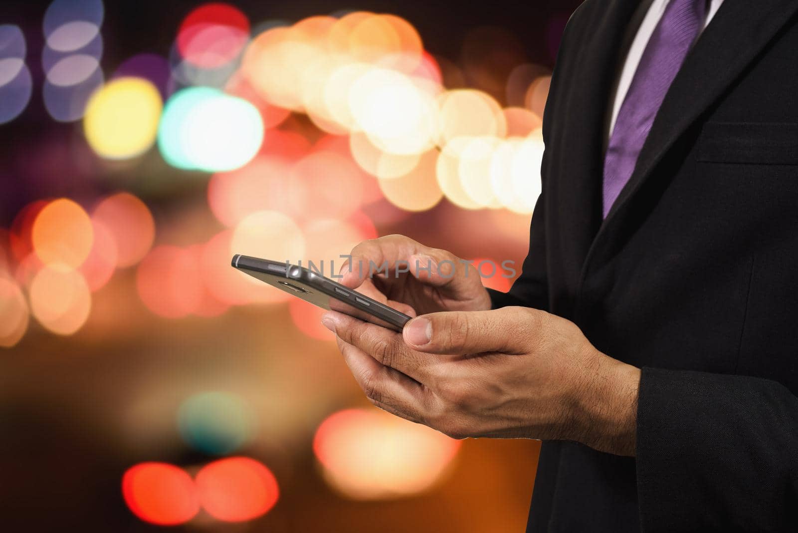 Business man using his mobile Phone night light road