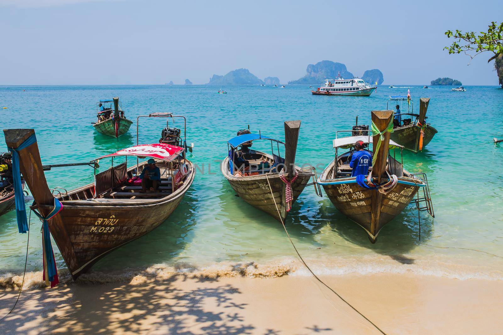 MAYA BAY, THAILAND - APRIL 14, 2014: Dramatic karst geography stands tall above traditional Thai longtail boats docked in the popular Maya Bay. by Wmpix