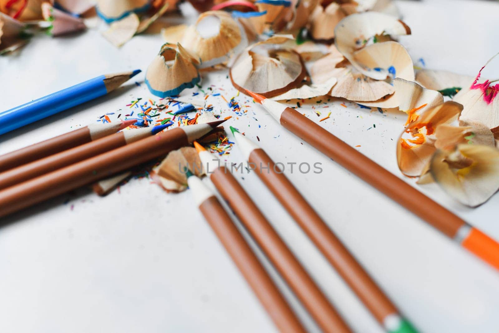 Wooden colorful pencils with sharpening shavings, on a white table