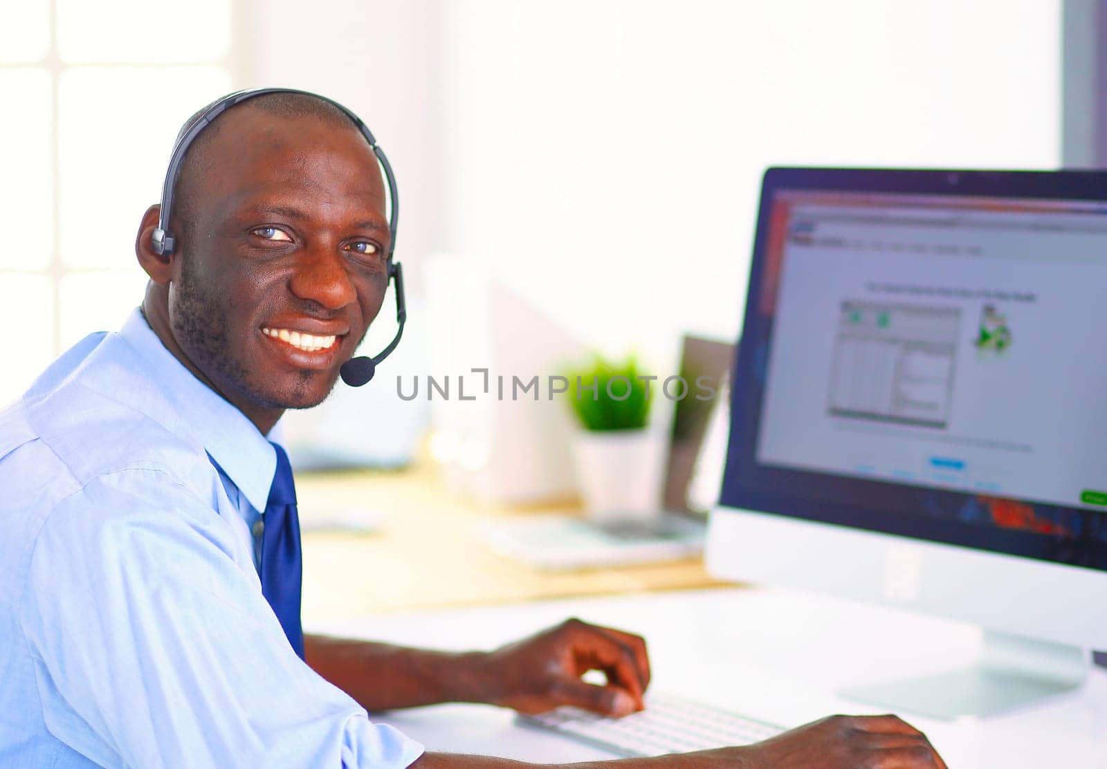 African american businessman on headset working on his laptop.