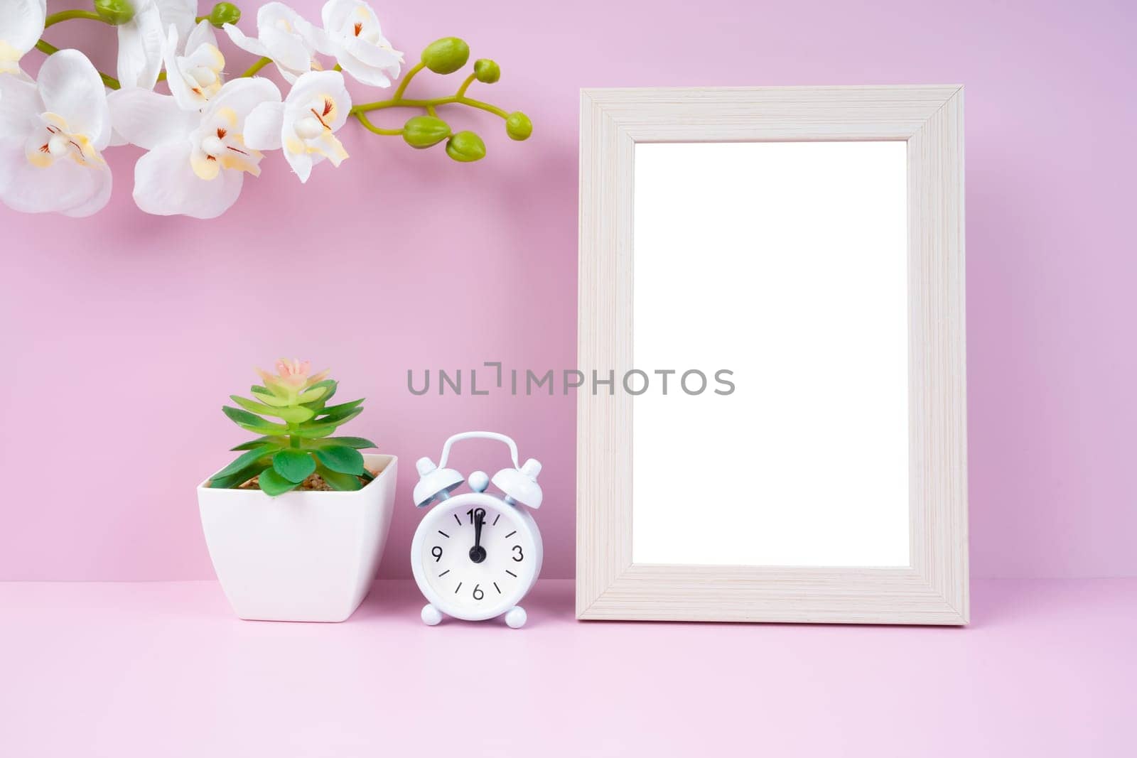 The Blank picture frame and alarm clock on pink color background with copy space and clipping path for the inside. by Gamjai