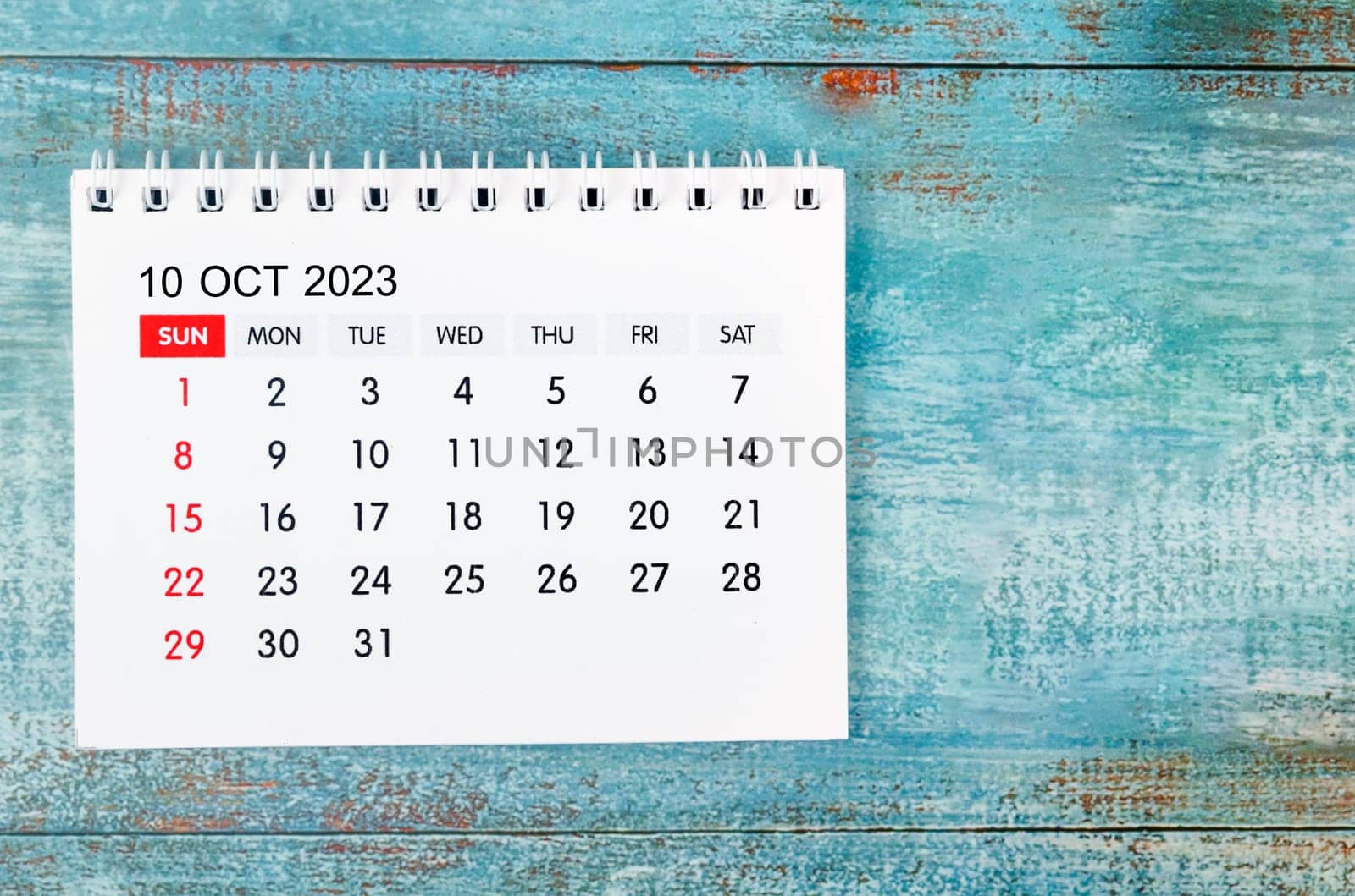 The October 2023 Monthly desk calendar for 2023 year on old blue wooden background. by Gamjai