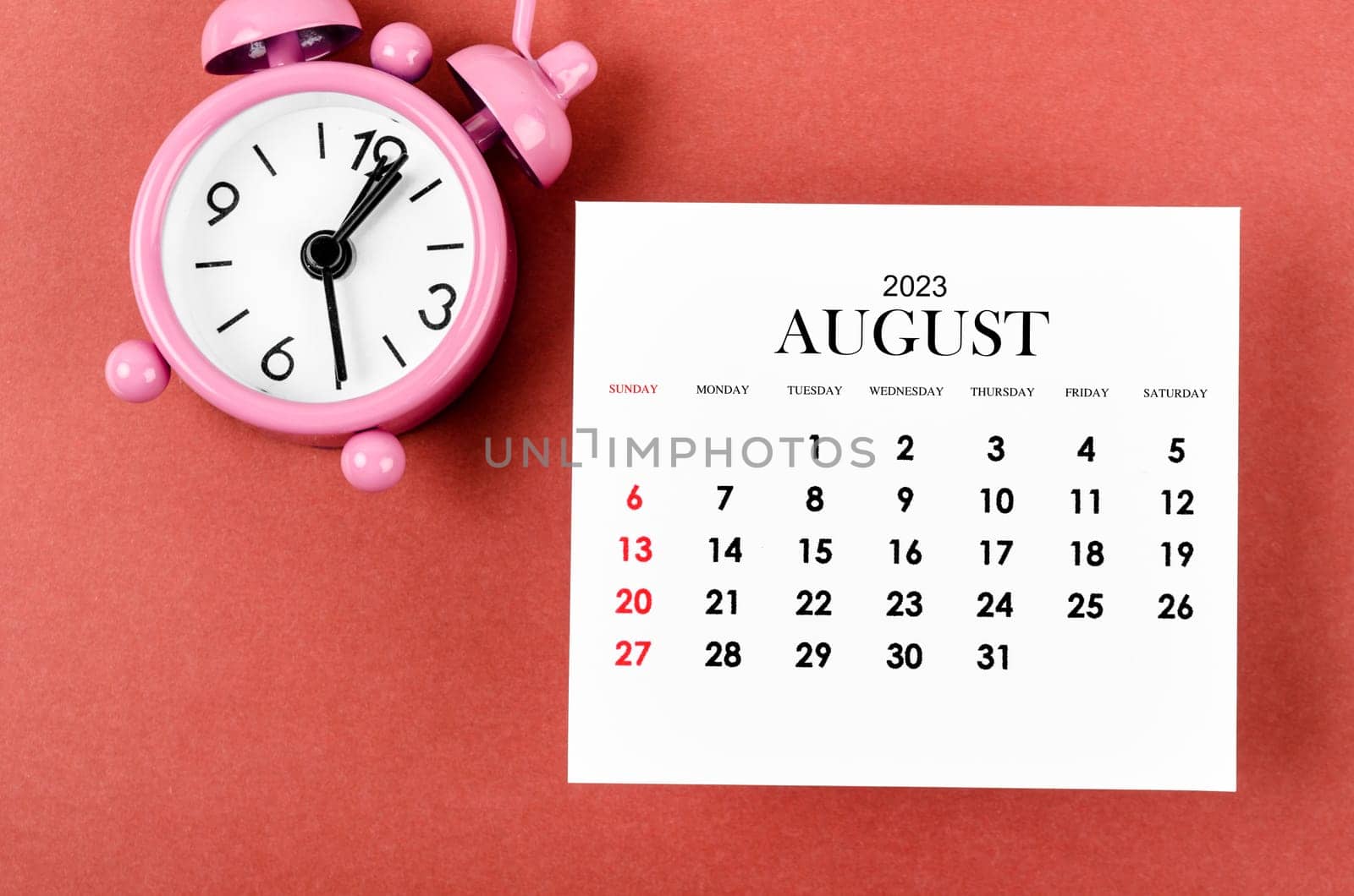 August 2023 Monthly calendar year with alarm clock on red color background.