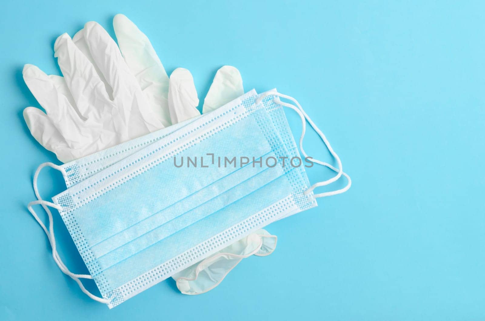The Disposable medical mask and gloves medical on a blue background. by Gamjai