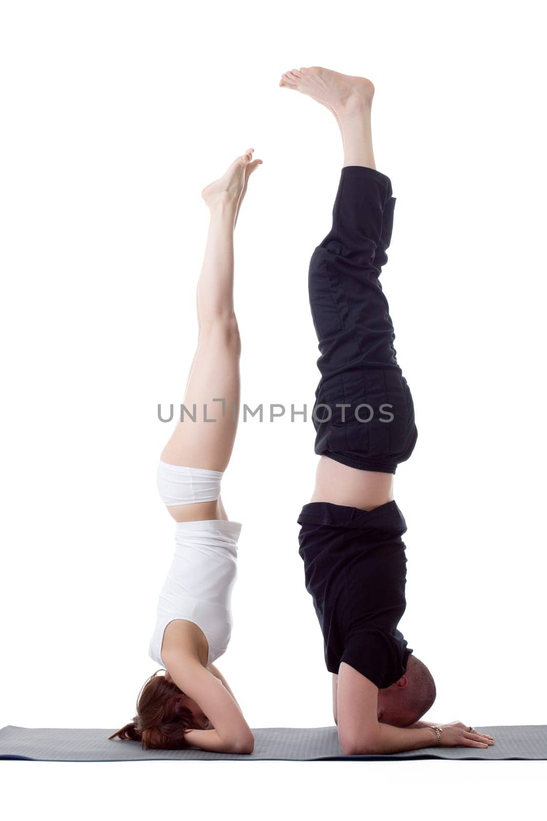 Pair of flexible yoga trainers doing handstand by rivertime