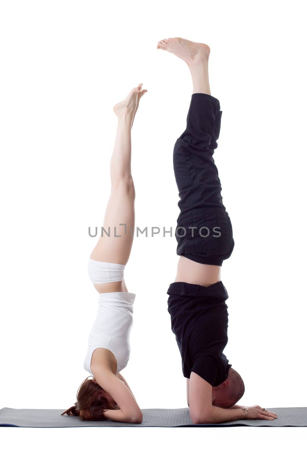 Couple of flexible yoga trainers doing handstand