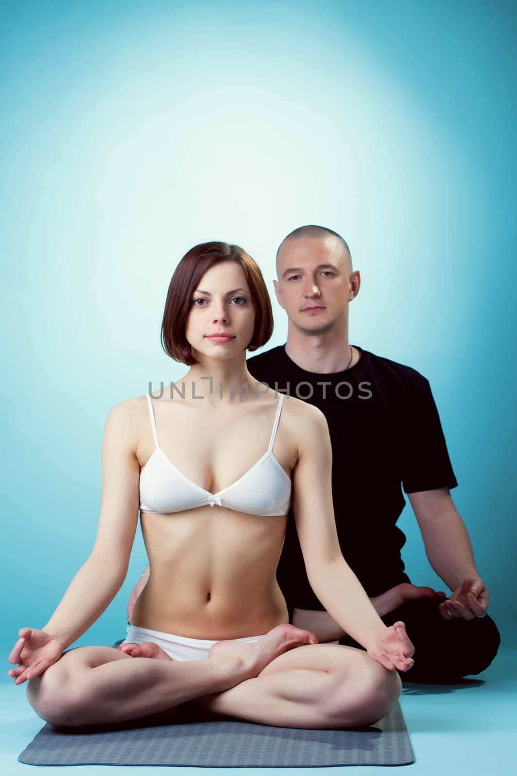 Image of healthy yoga instructors posing at camera, on blue background