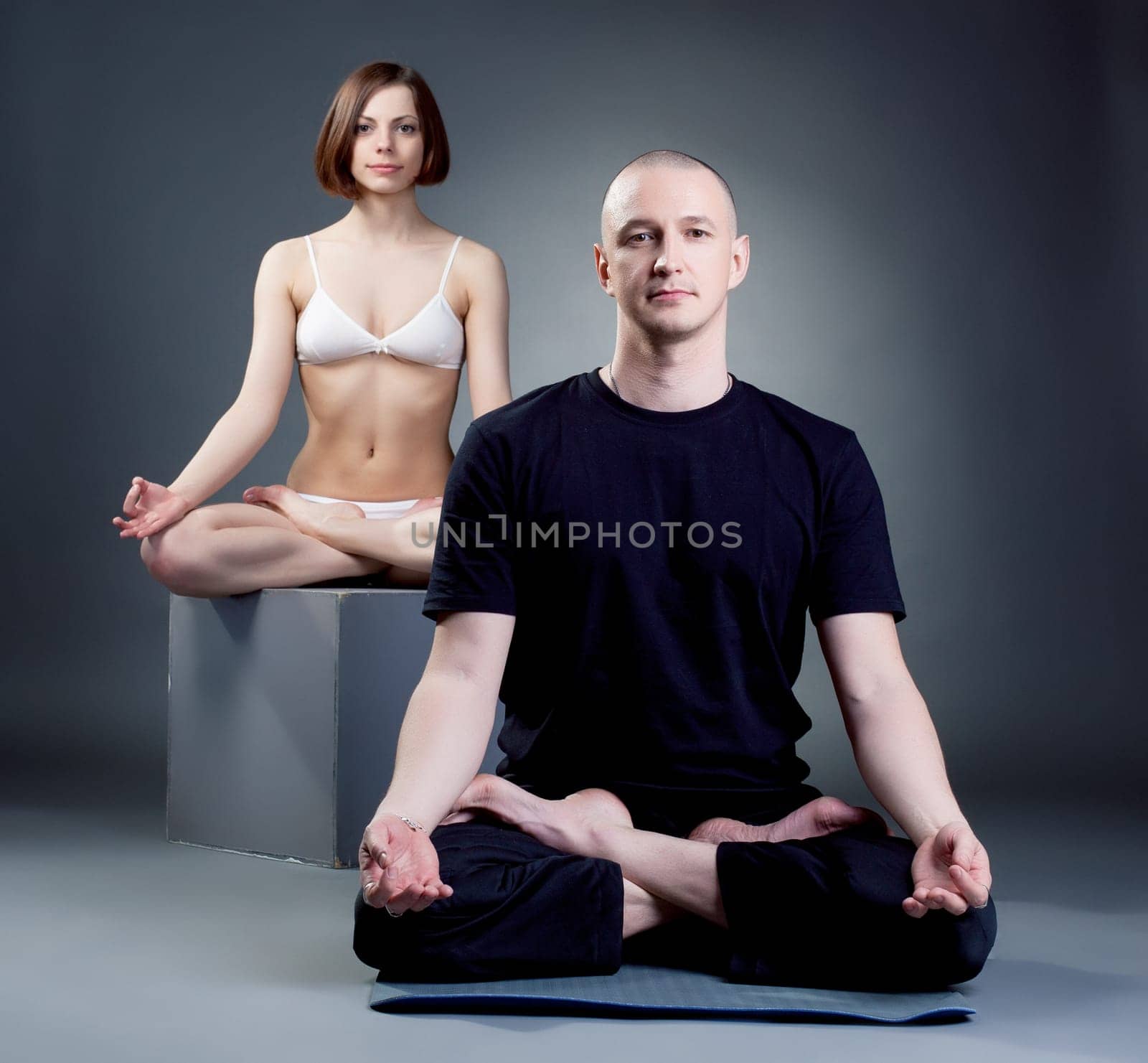 Shot of meditating yoga trainers, on gray backdrop by rivertime