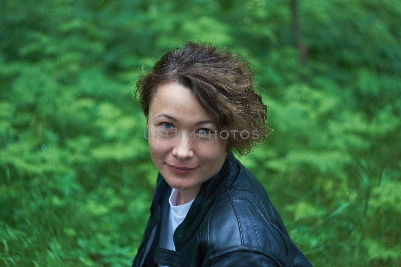 Amazing joyful pretty girl with long short hair. posing outdoors. leather jacket, dark hair, close-up, portrait of a street fashion model looking straight