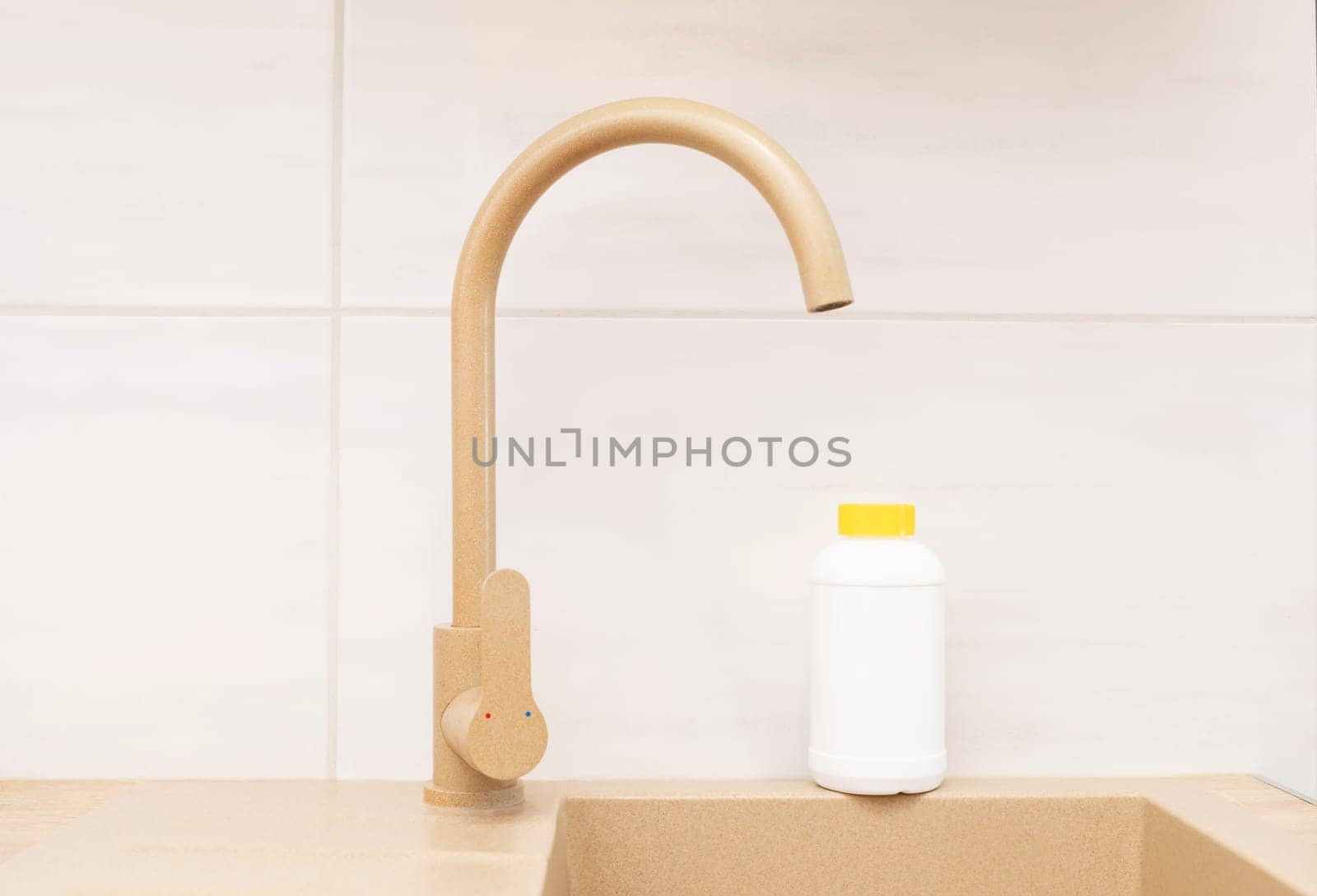 Pipe Drain Granules in White Plastic Bottle With Yellow Cap On Kitchen Sink In Cook Room. Clog Cleaner, Housework Help. Cleaning enzymes, Prevention of Blockages In Traps. Horizontal plane.