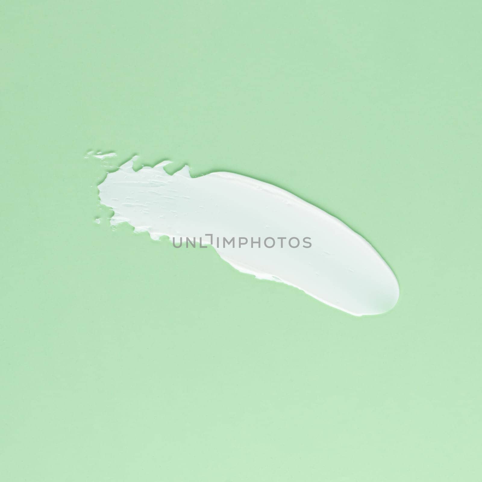 Smear of white cream for face and body on a green background