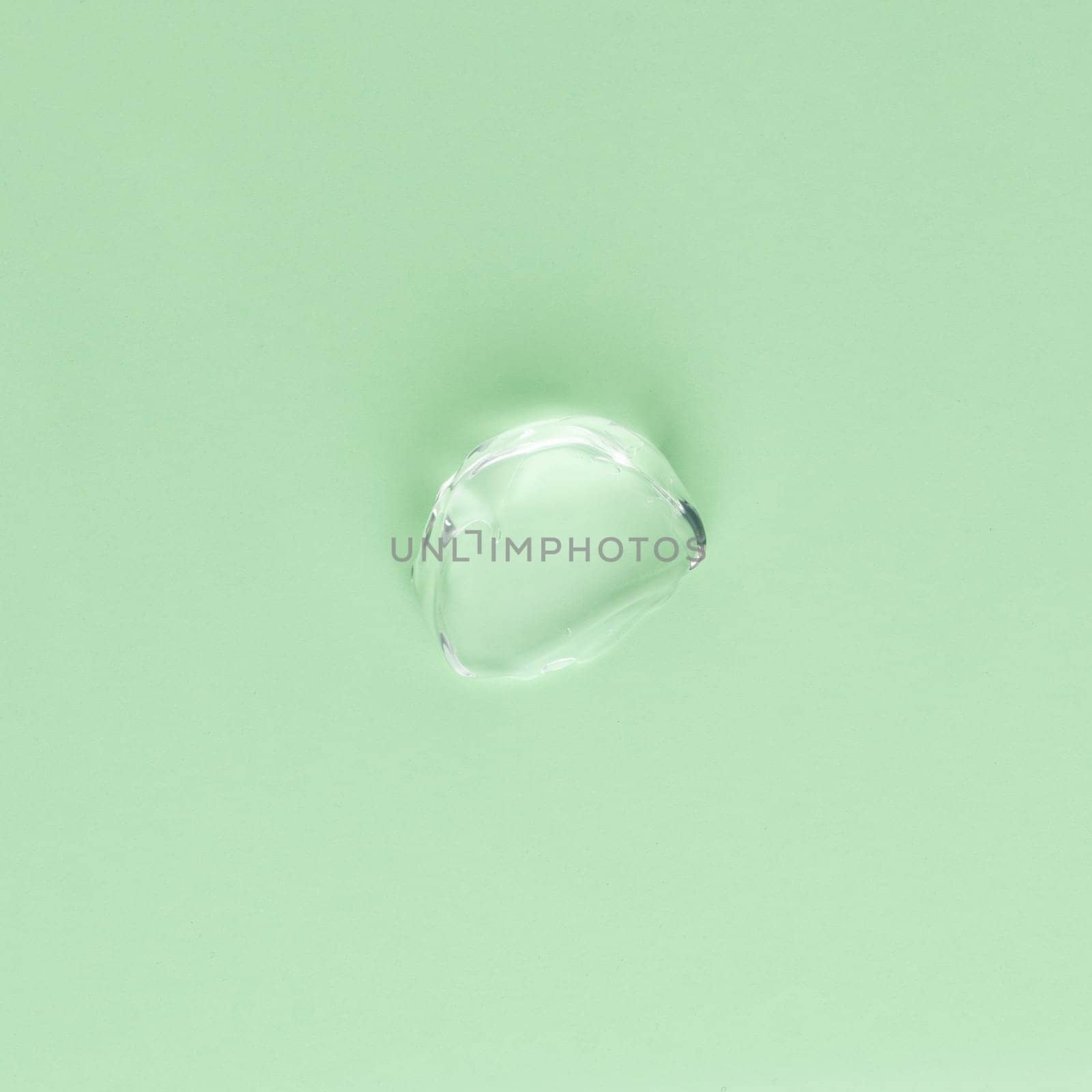 Drop of transparent face and body cream on a green background