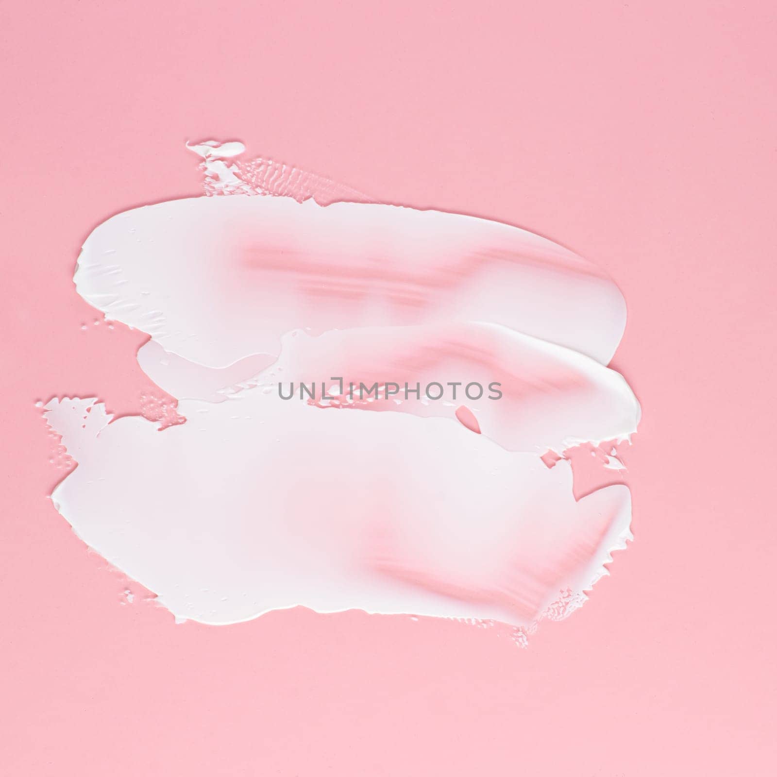 Smear of white cream for face and body on a pink background