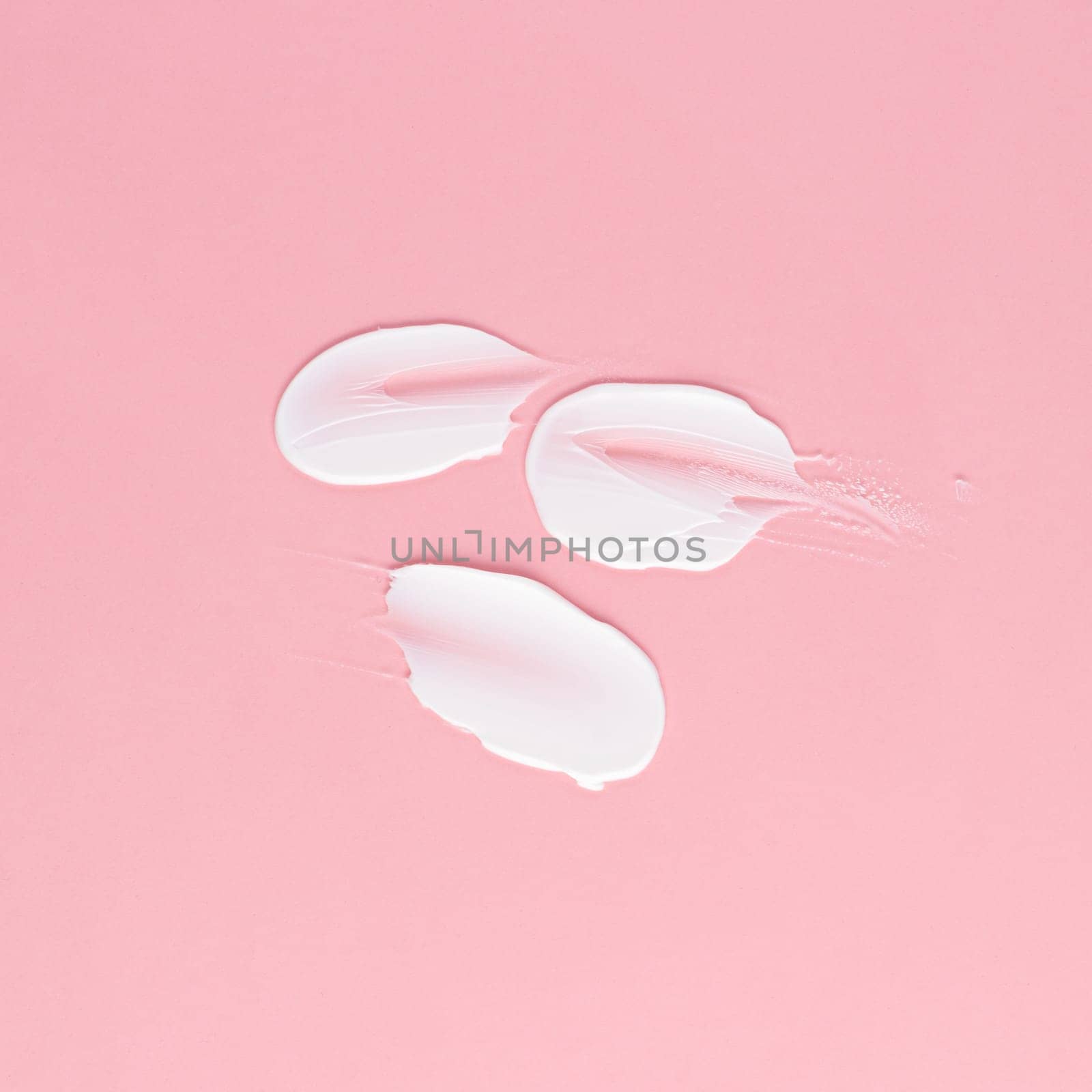 Smear of white cream for face and body on a pink background by A_Karim