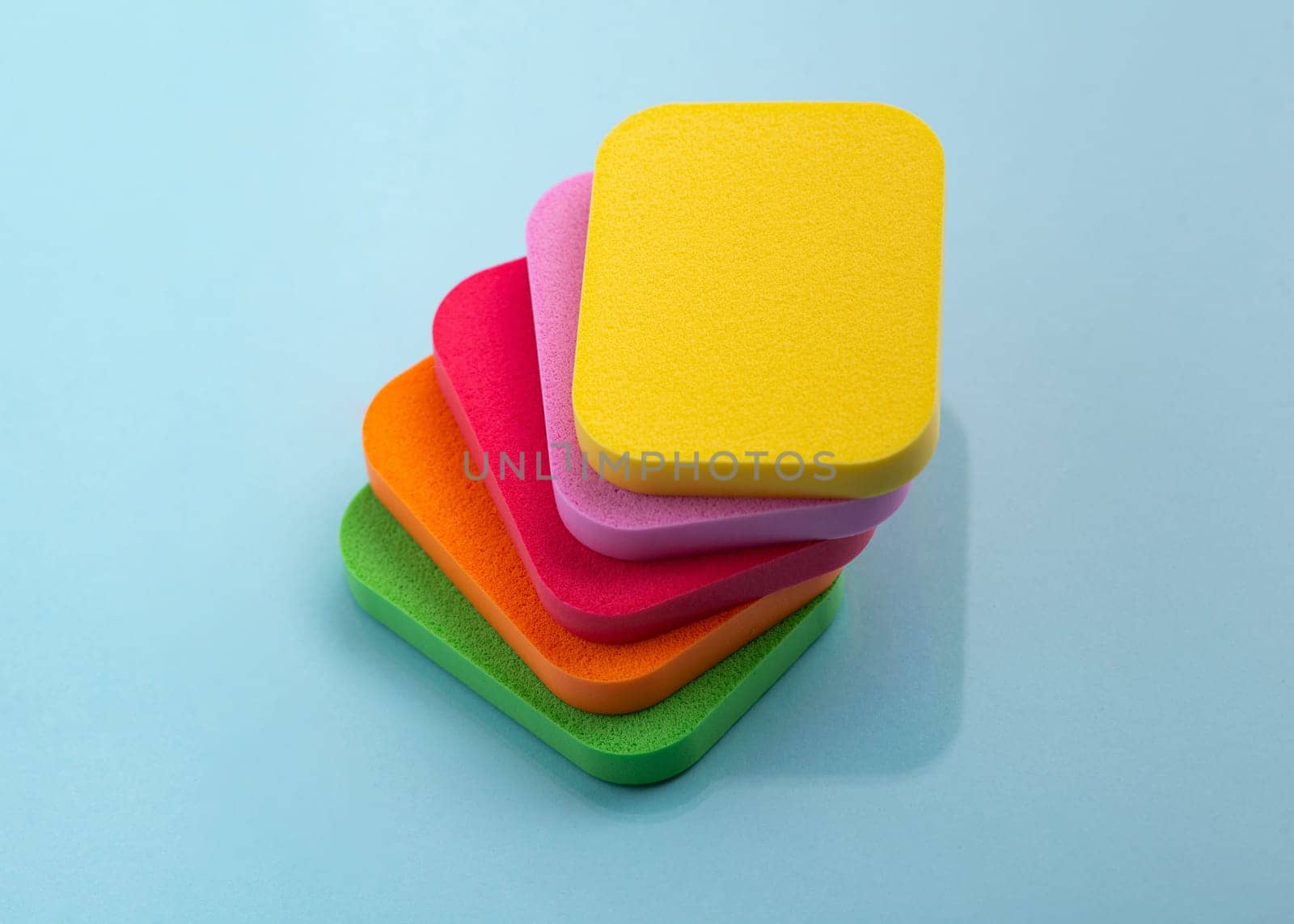 Heap of colorful cosmetic sponges on blue background. Top view by A_Karim