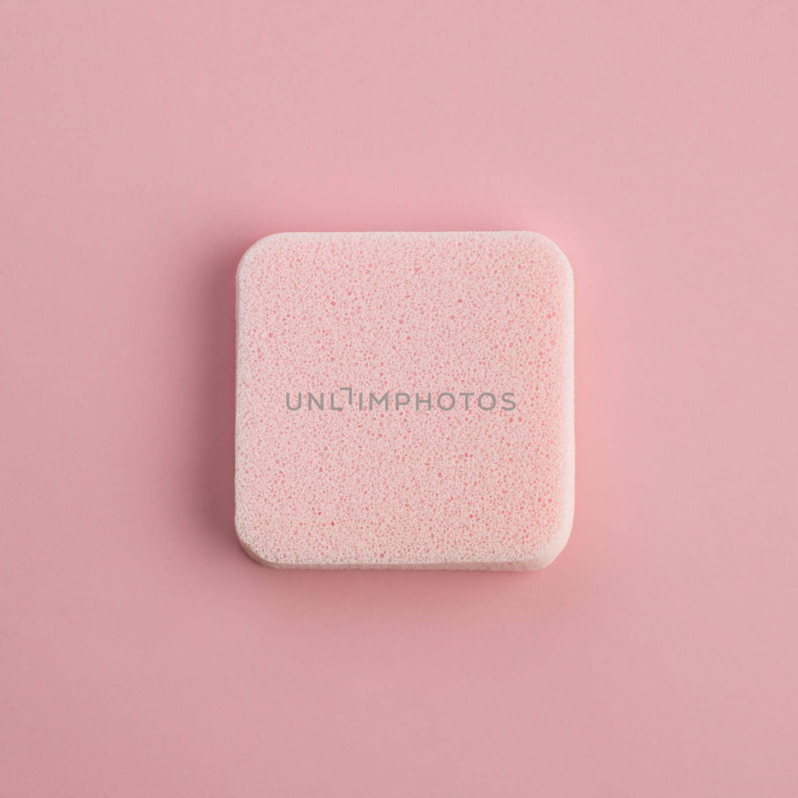 Cosmetic sponge on a pink background. Top view