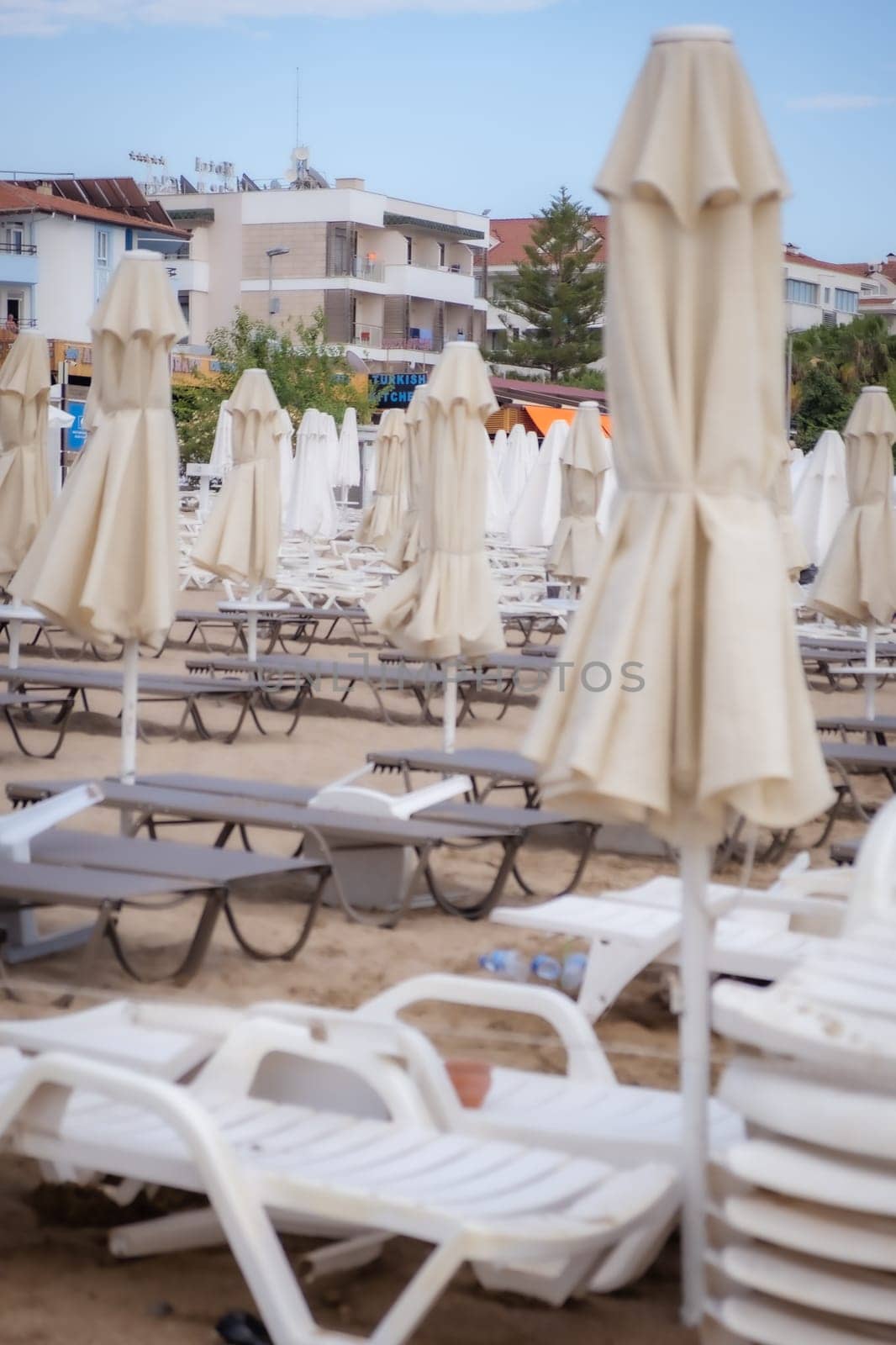 Umbrellas and sun loungers in the assembled state on the beach. by AnatoliiFoto