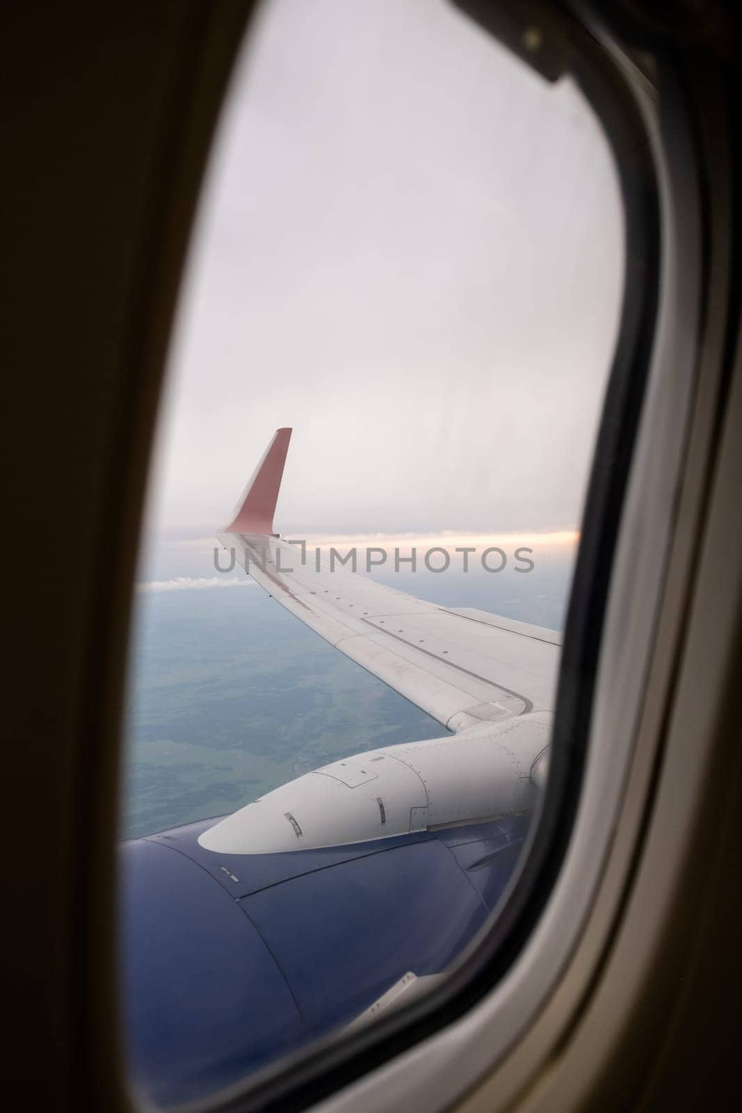 Airplane flight. Wing of an airplane flying above the clouds. View from the window of the plane. Airplane, Aircraft. Traveling by air. Aircraft's wing and land seen through the illuminator.