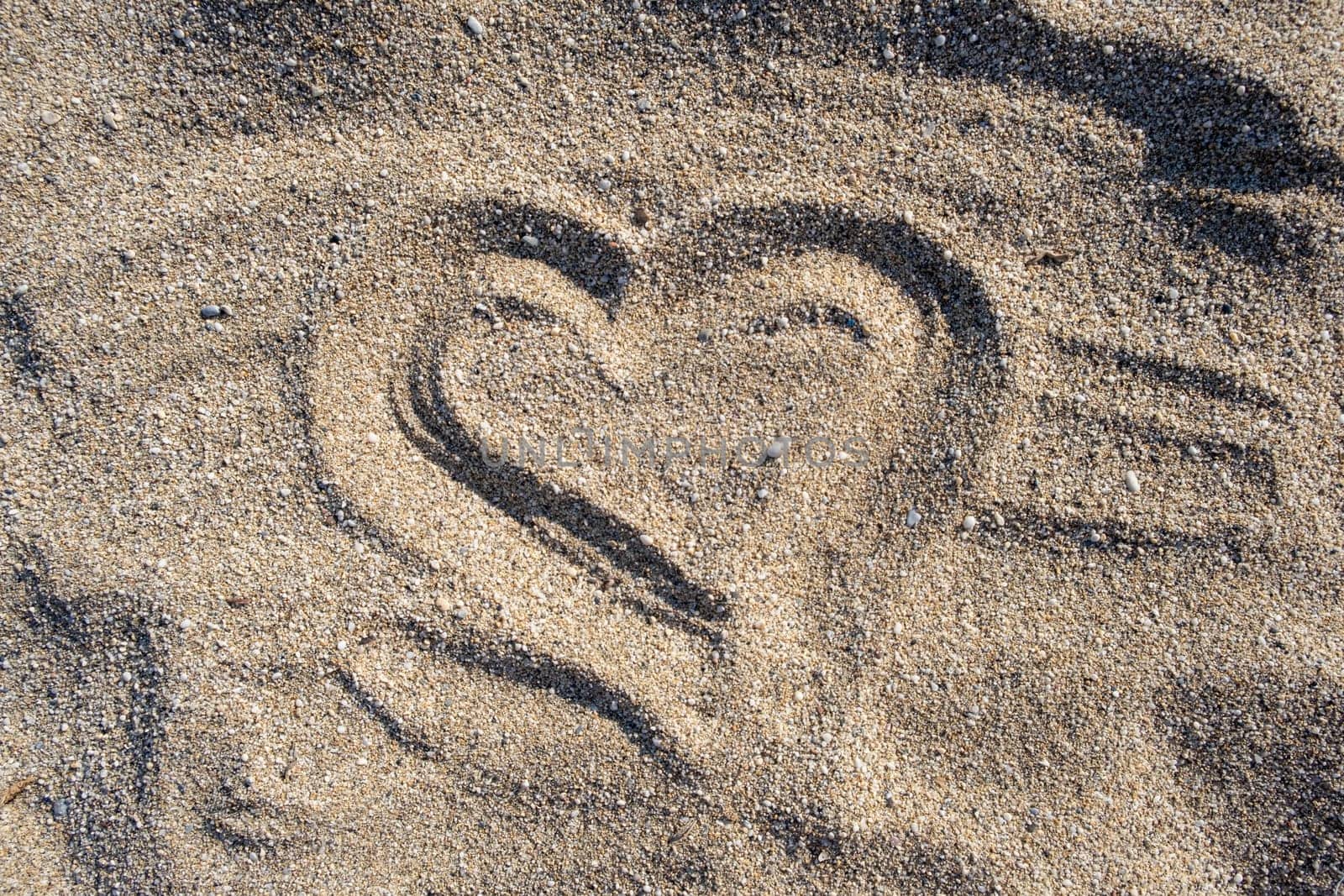 Drawing heart shape love concept on sand at the beach with vacation holiday summer travel background. Heart shape and footprint on sand.