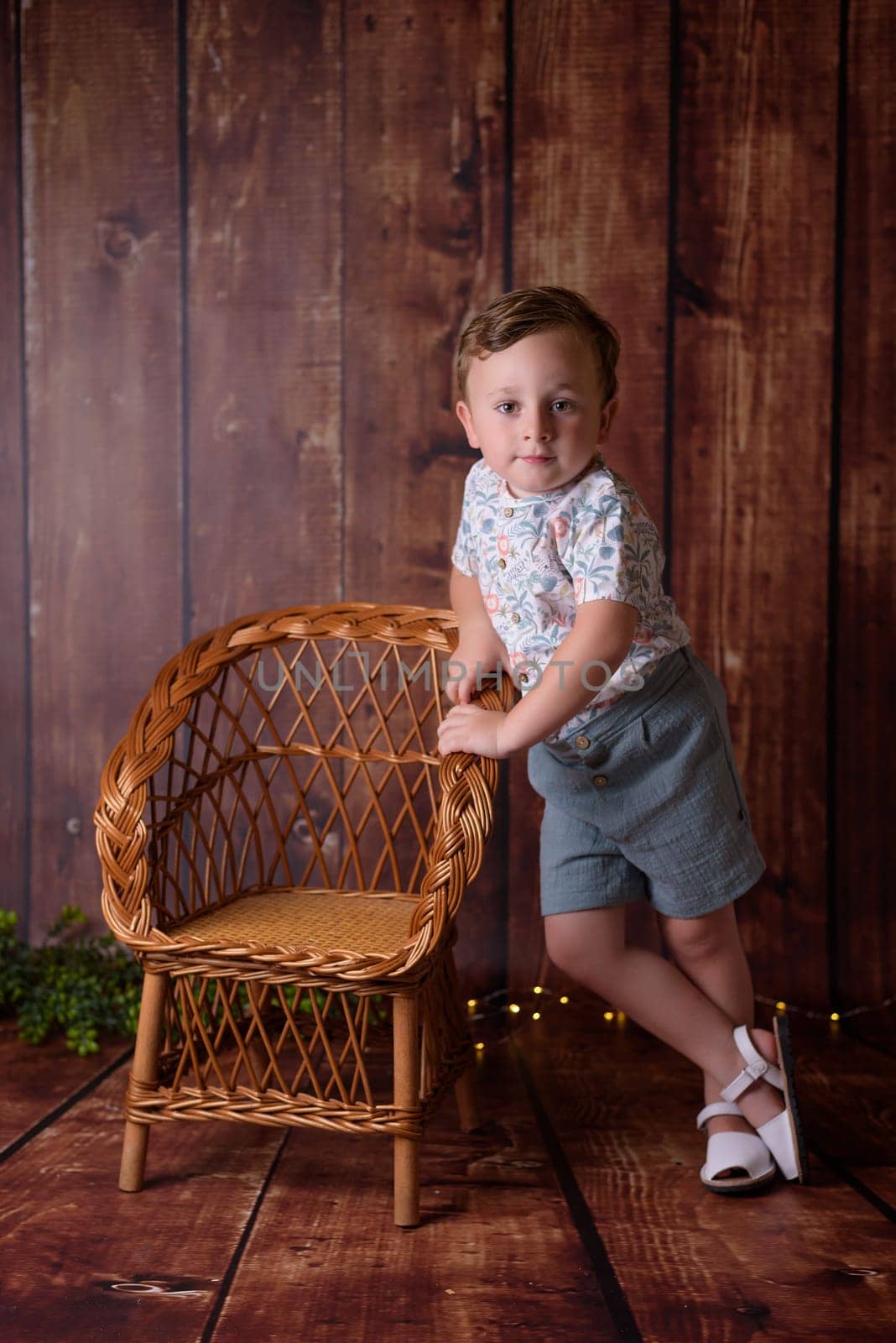 Portrait of sitting boy, isolated on wooden background.