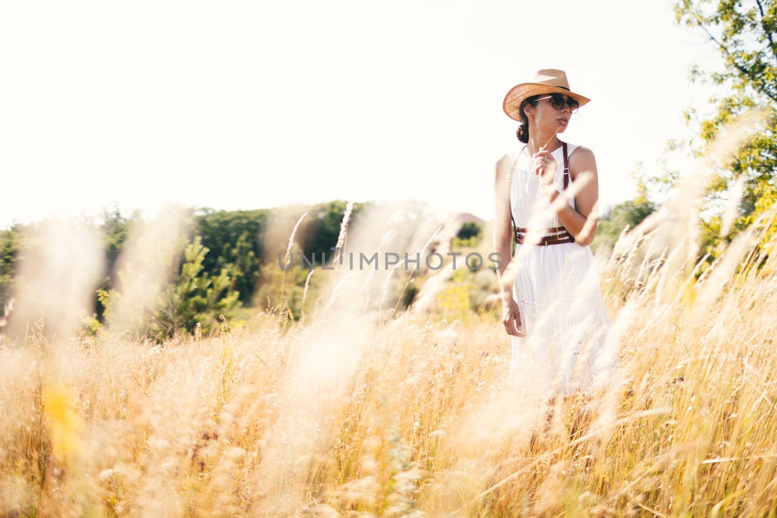 Portrait of woman in golden sunset light in outdoor meadow. Springtime and summer lifestyle. Wellbeing and zen like meditation activity in outdoor. Loving life. by sarymsakov