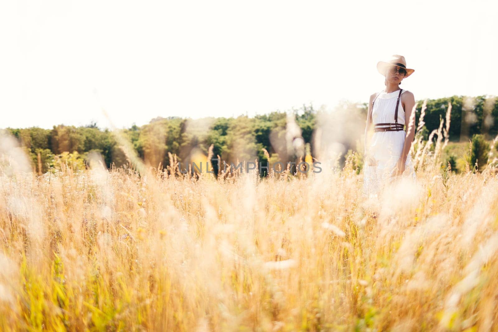 Beautiful girl in a linen dress in a wheat field. Summer vacation, traveling. Bohemian, modern hippie style.