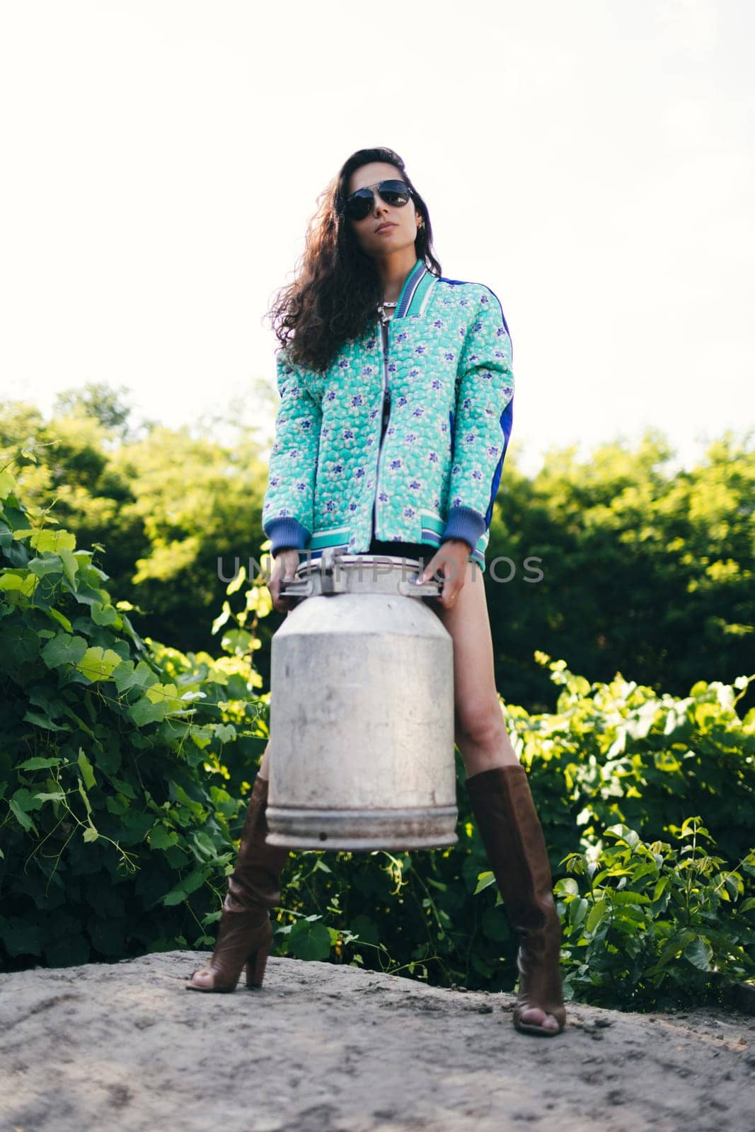 Young fashionable farmer woman posing on camera while holding milk can