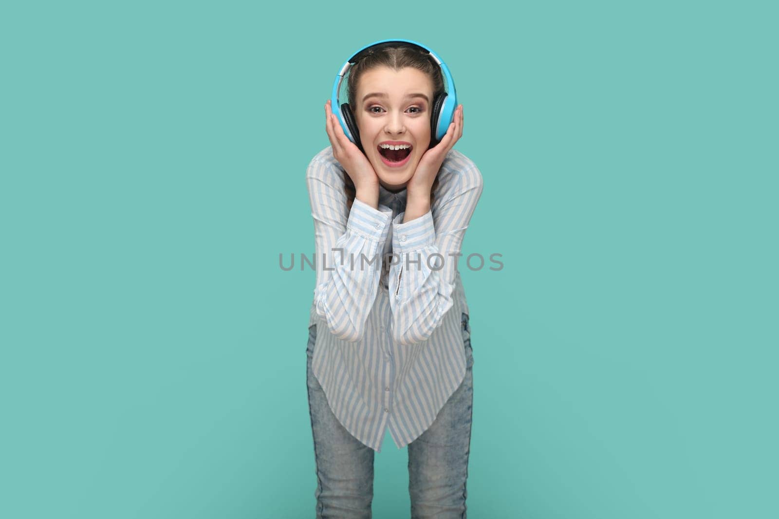 Amazed positive joyful teenager girl listening music on headphones, hearing favorite song. by Khosro1