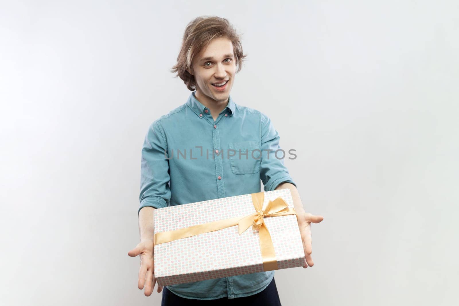 Satisfied friendly man standing with gift in hands, giving present to her girl friend on birthday. by Khosro1