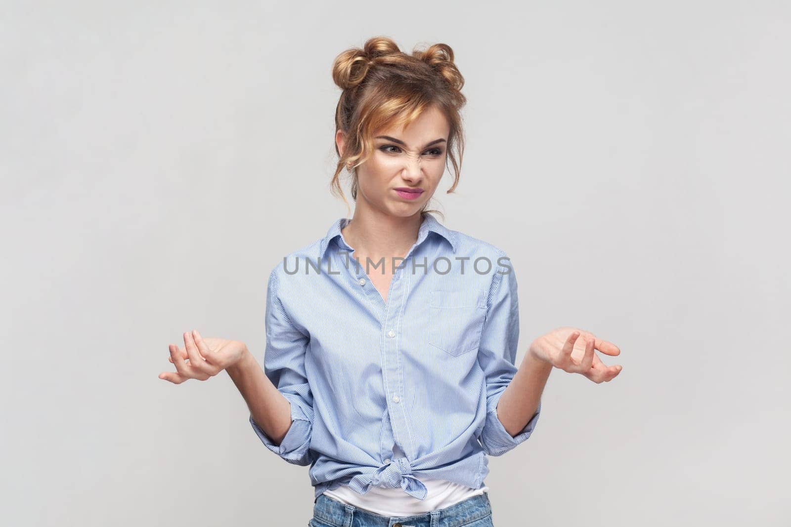 How could you. Portrait of annoyed indignant blonde woman spreads palms, smirks face, looks angrily at camera, quarrels with someone, feels puzzled. Indoor studio shot isolated on gray background.