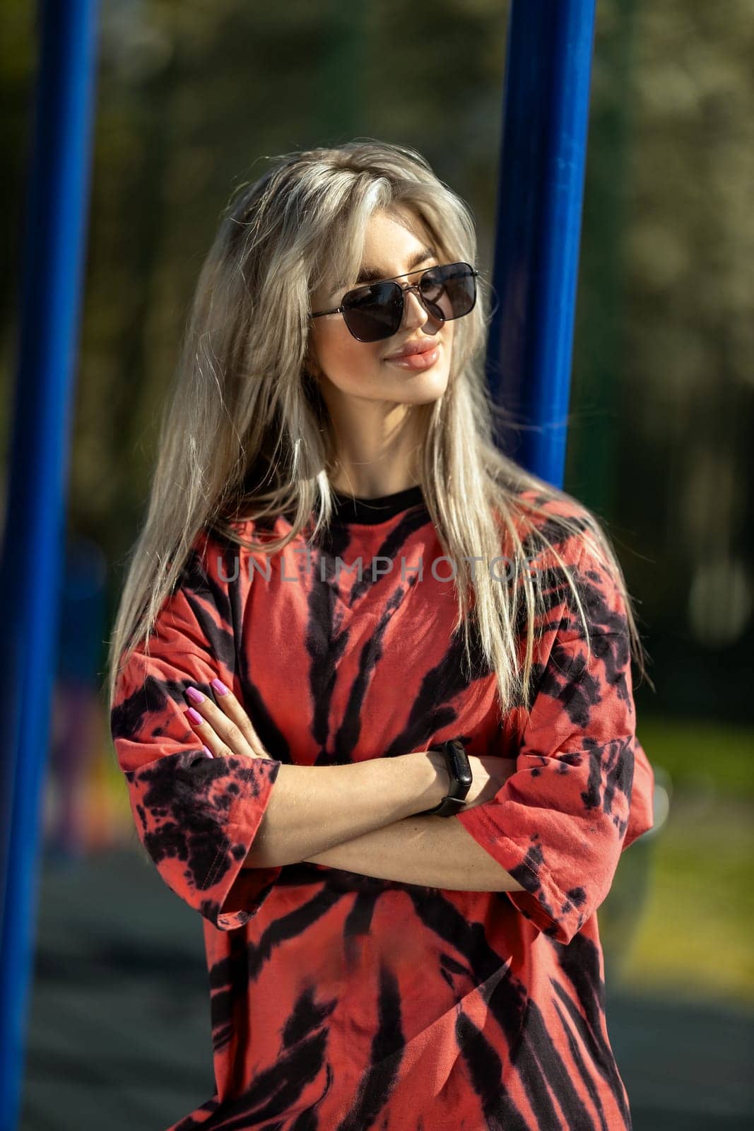 blonde athletic girl stands on the sports ground in a t-shirt, breeches, white sneakers and white headphones