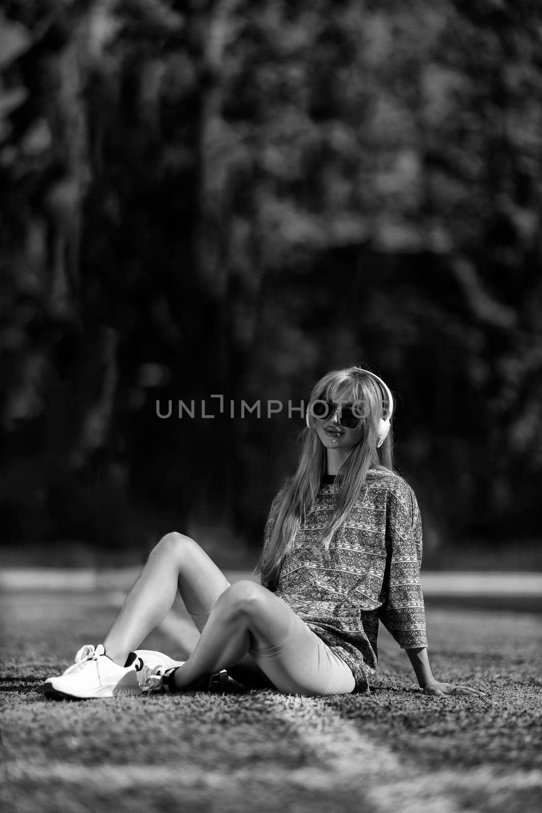 blonde athletic girl sitting on the football field black and white
