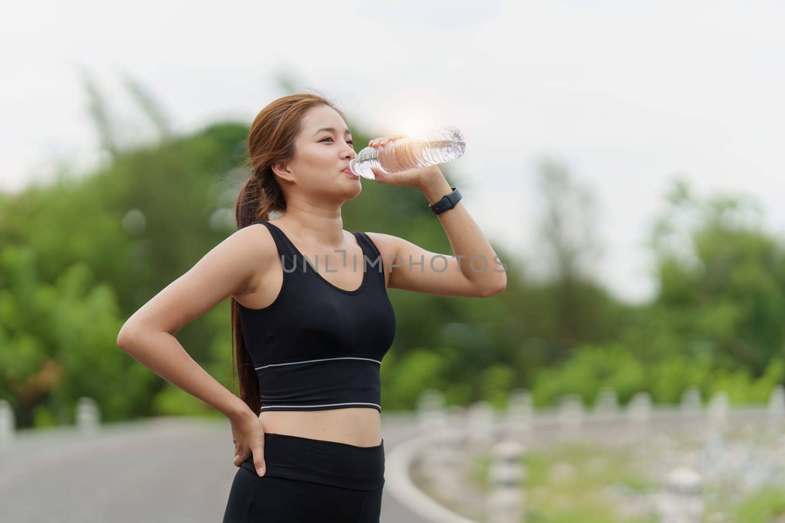 Woman drinking water after sport activities. Female exercising at outdoor park.