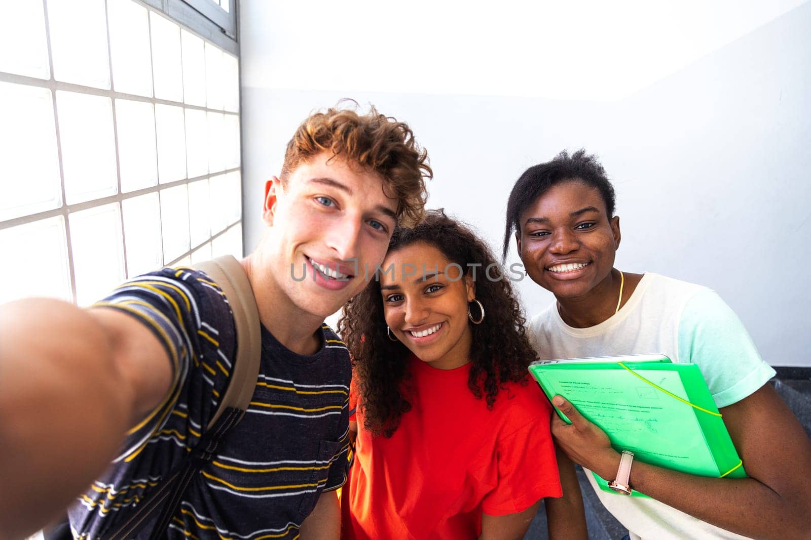 Happy group of multiracial teen friends taking a selfie in high school corridor. Back to school concept. Friendship concept.