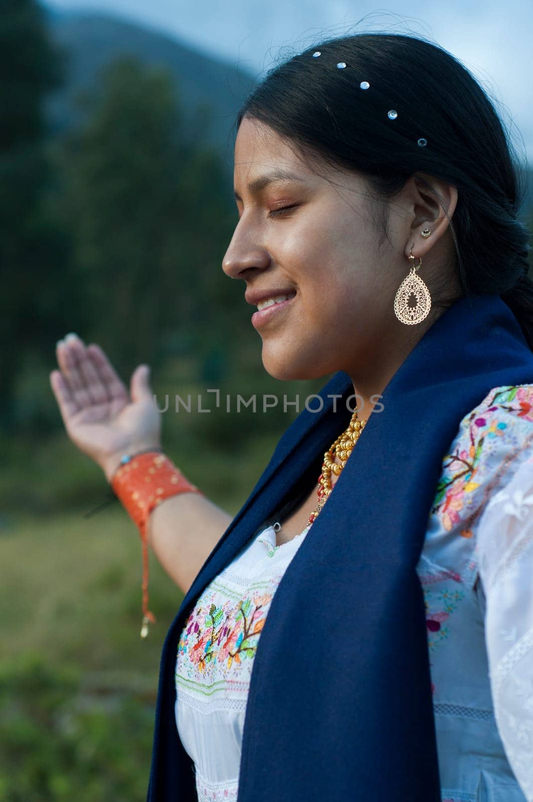 indigenous woman in a ritual in nature with her eyes closed and her arms crossed in traditional dress of her culture. High quality photo