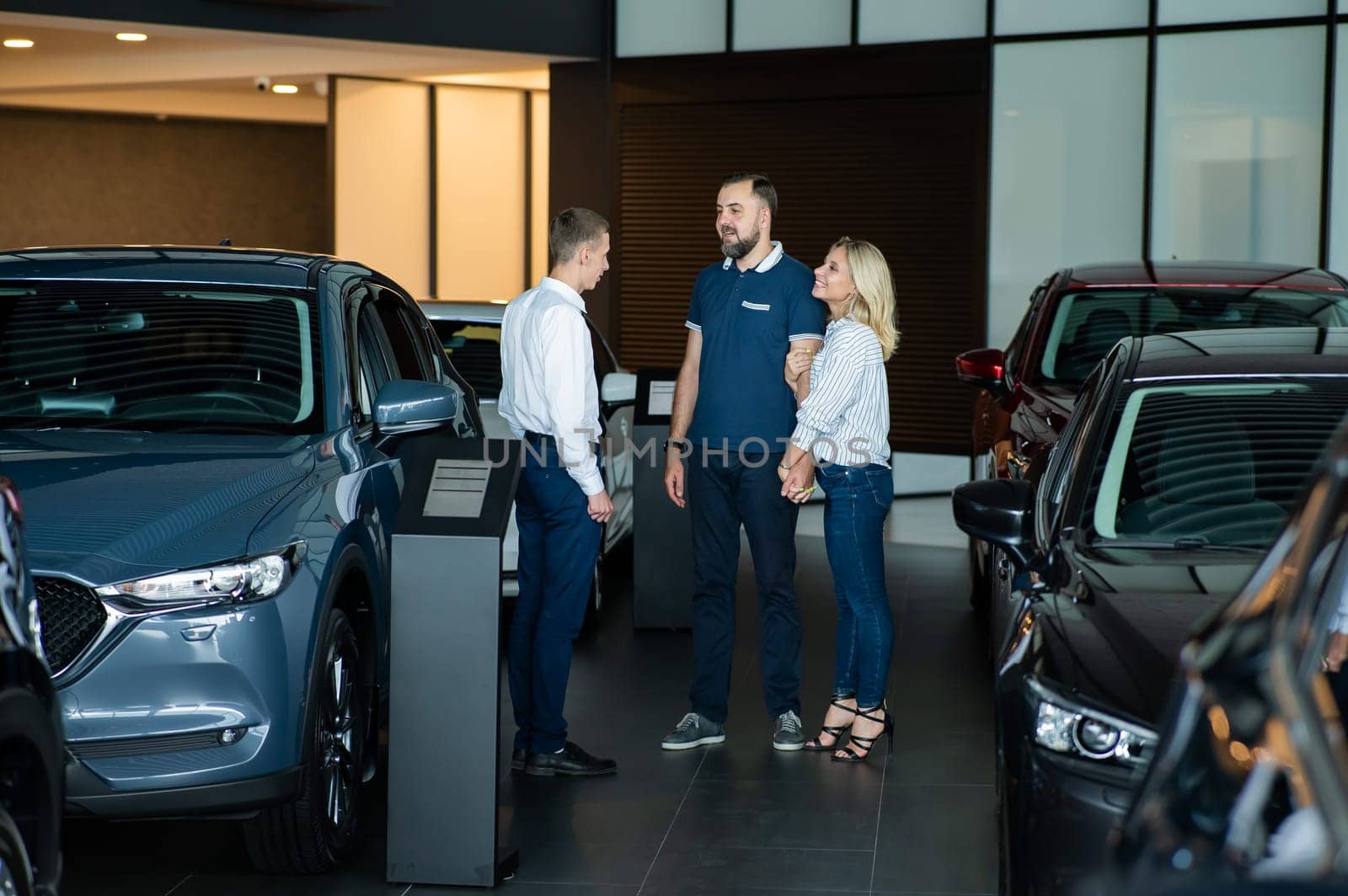 A caucasian couple shakes hands with a salesperson while buying a car