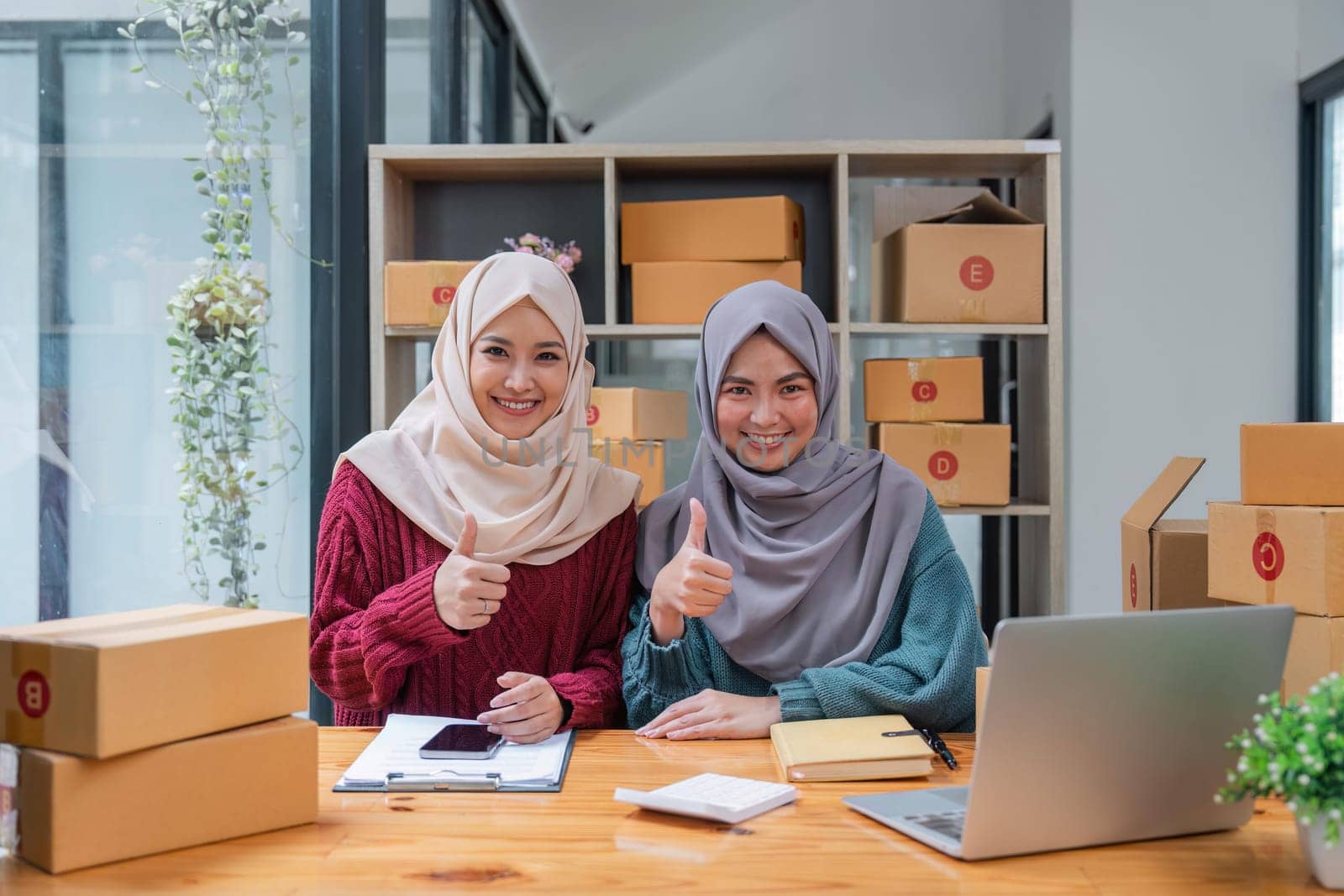 two muslim woman thumbs up working online sales of they made at home. small business muslim selling online.