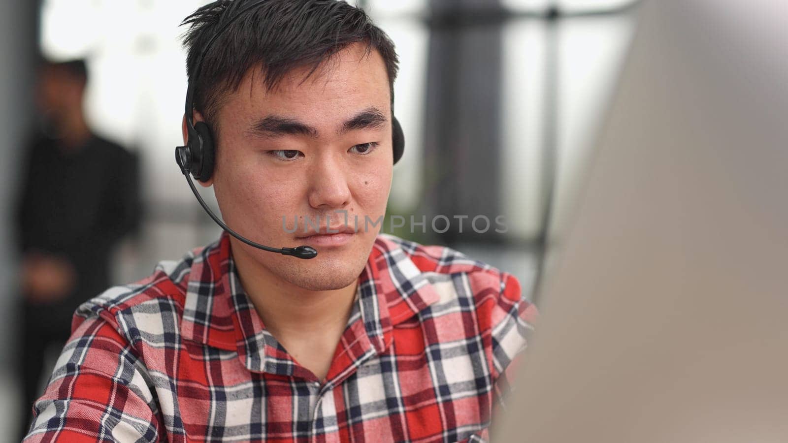 Young asian businessman working on laptop computer wearing headphone at home by Prosto