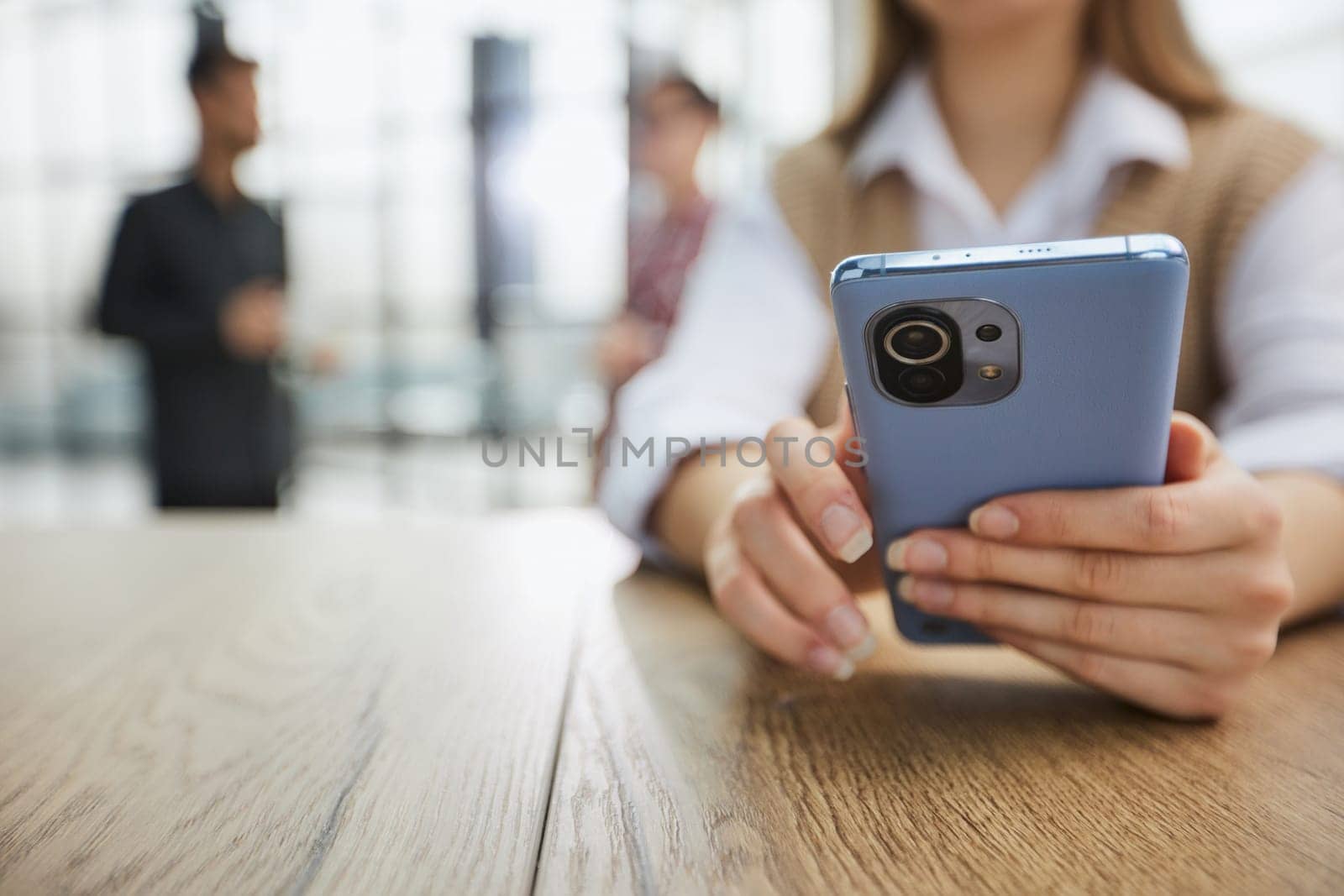 Cheerful student woman sitting at table break holding mobile phone surfing internet by Prosto
