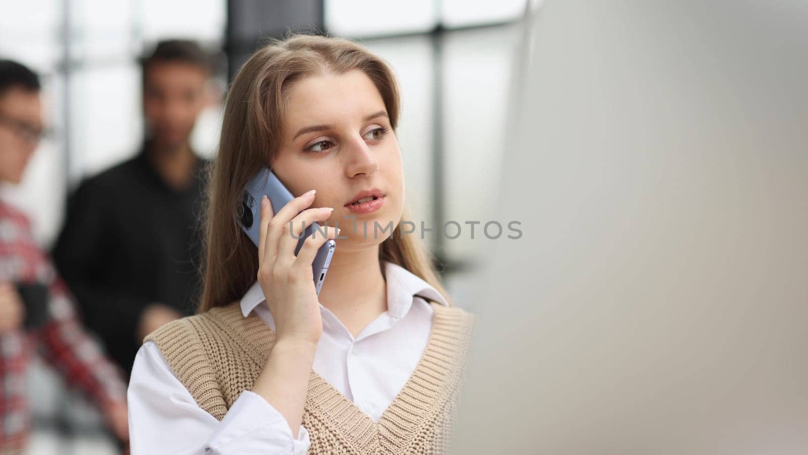 Young woman sales manager talking on cell phone using laptop working online on computer.