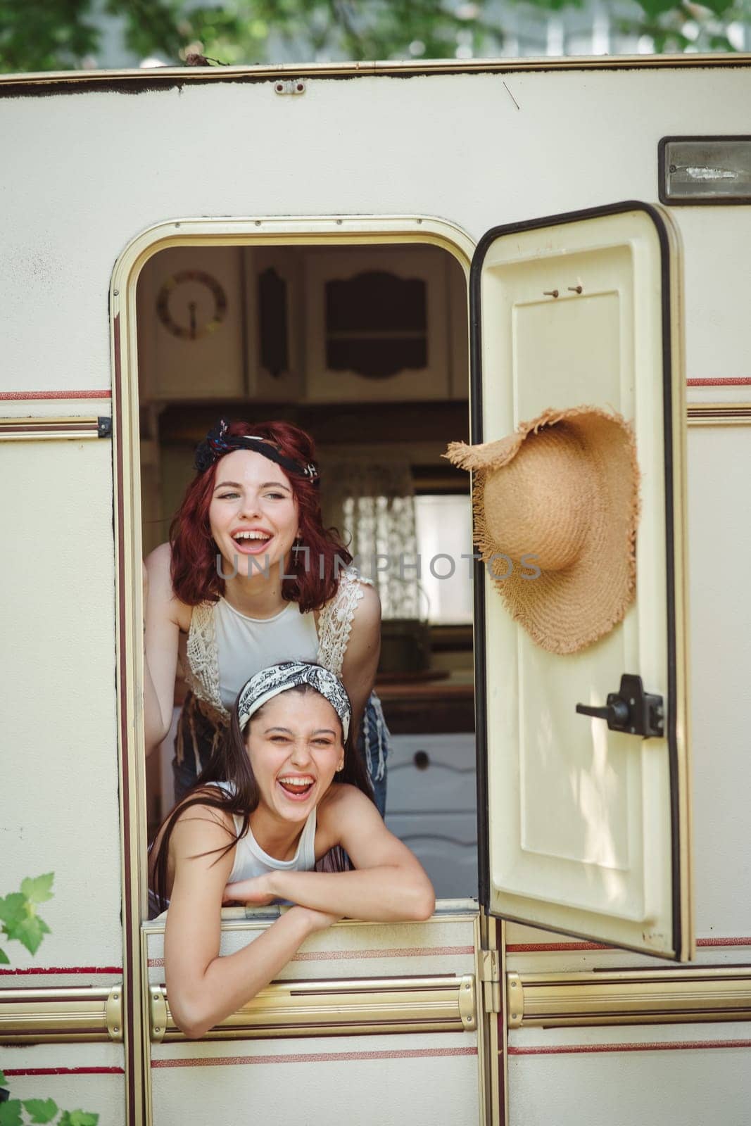 Happy hippie friends are having a good time together in camper trailer. Holiday, vacation, trip concept. High quality photo