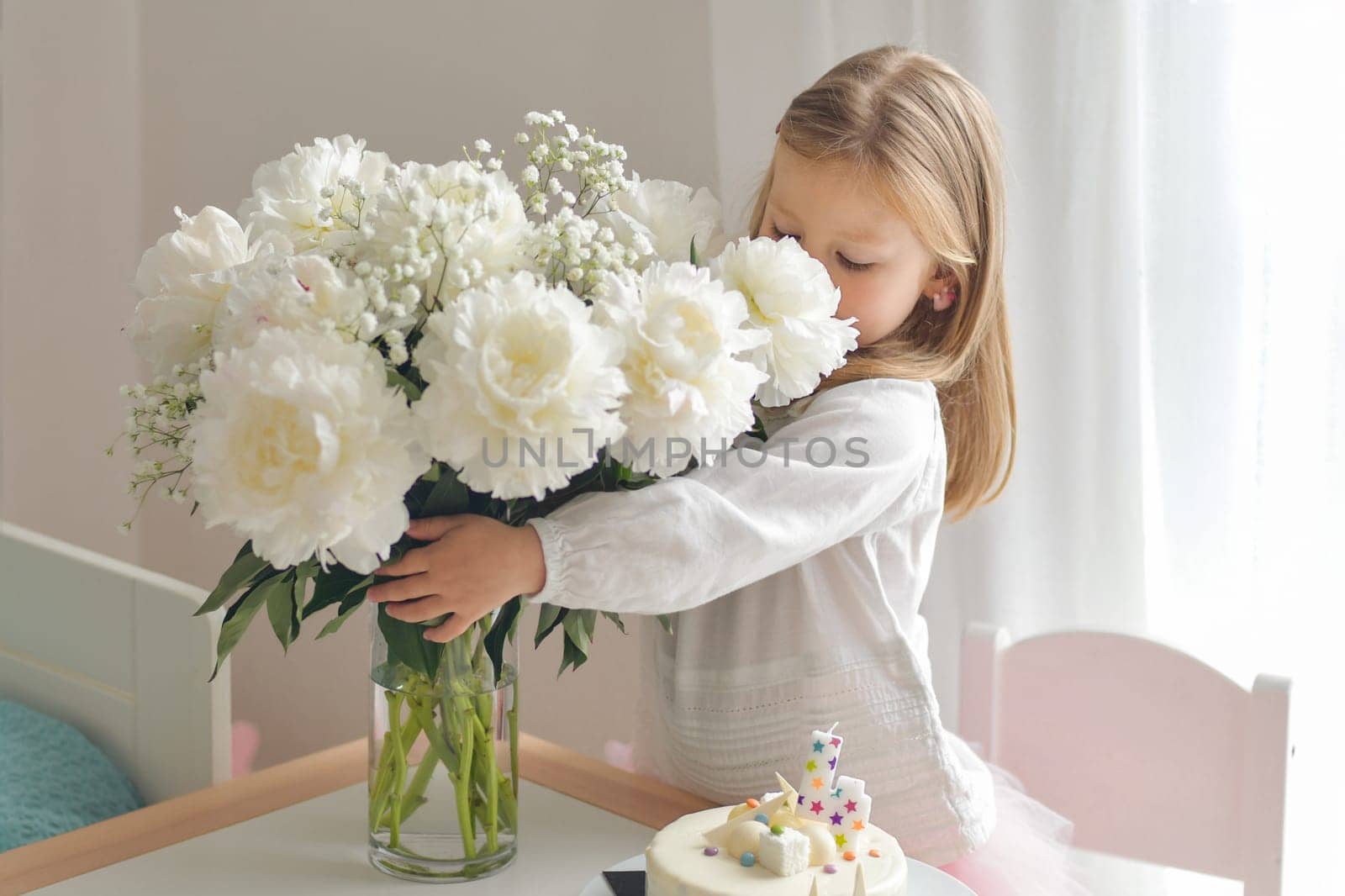 A little girl smelling the white peonies by Godi
