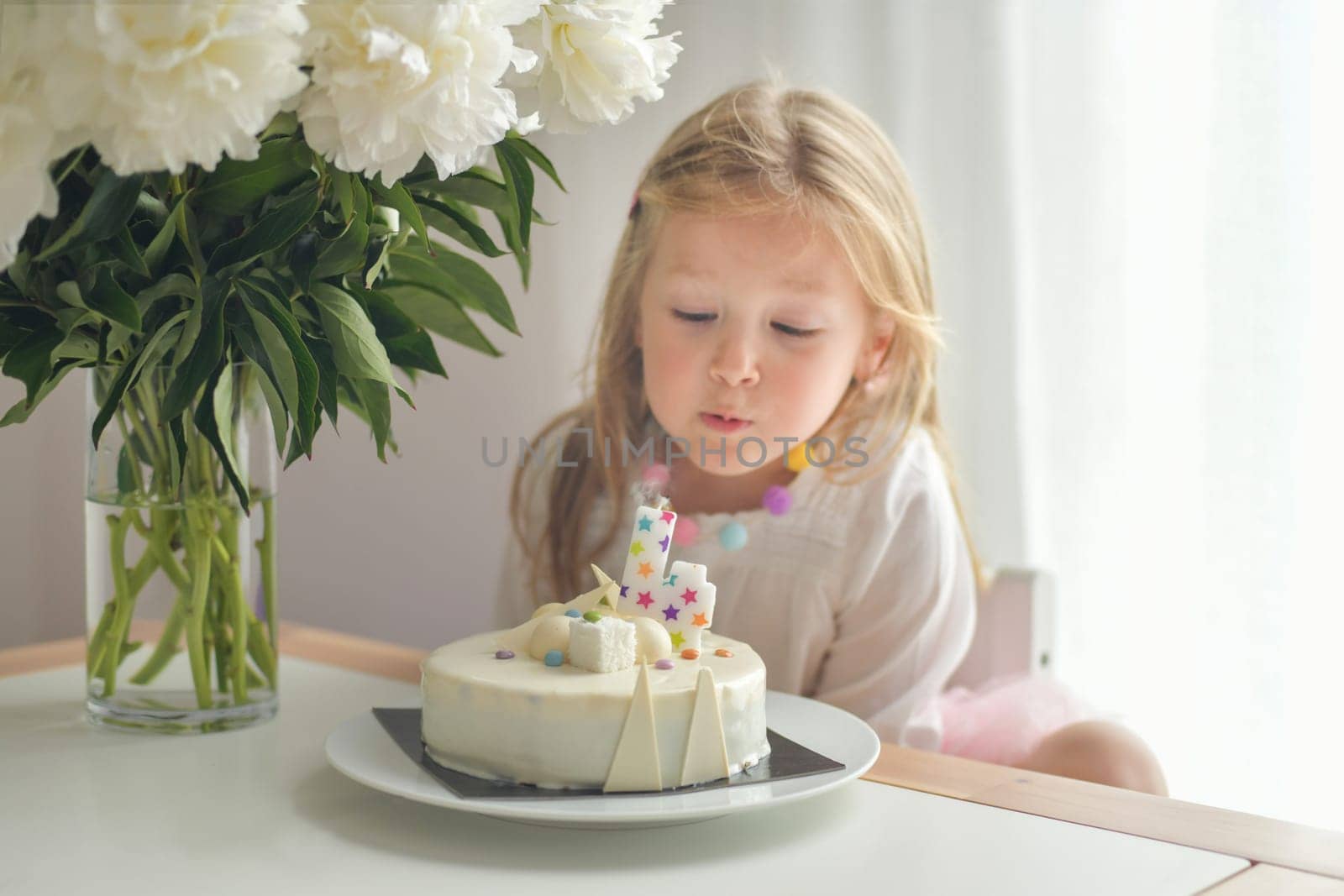 A girl of four years old making wish blowing candles on a cake